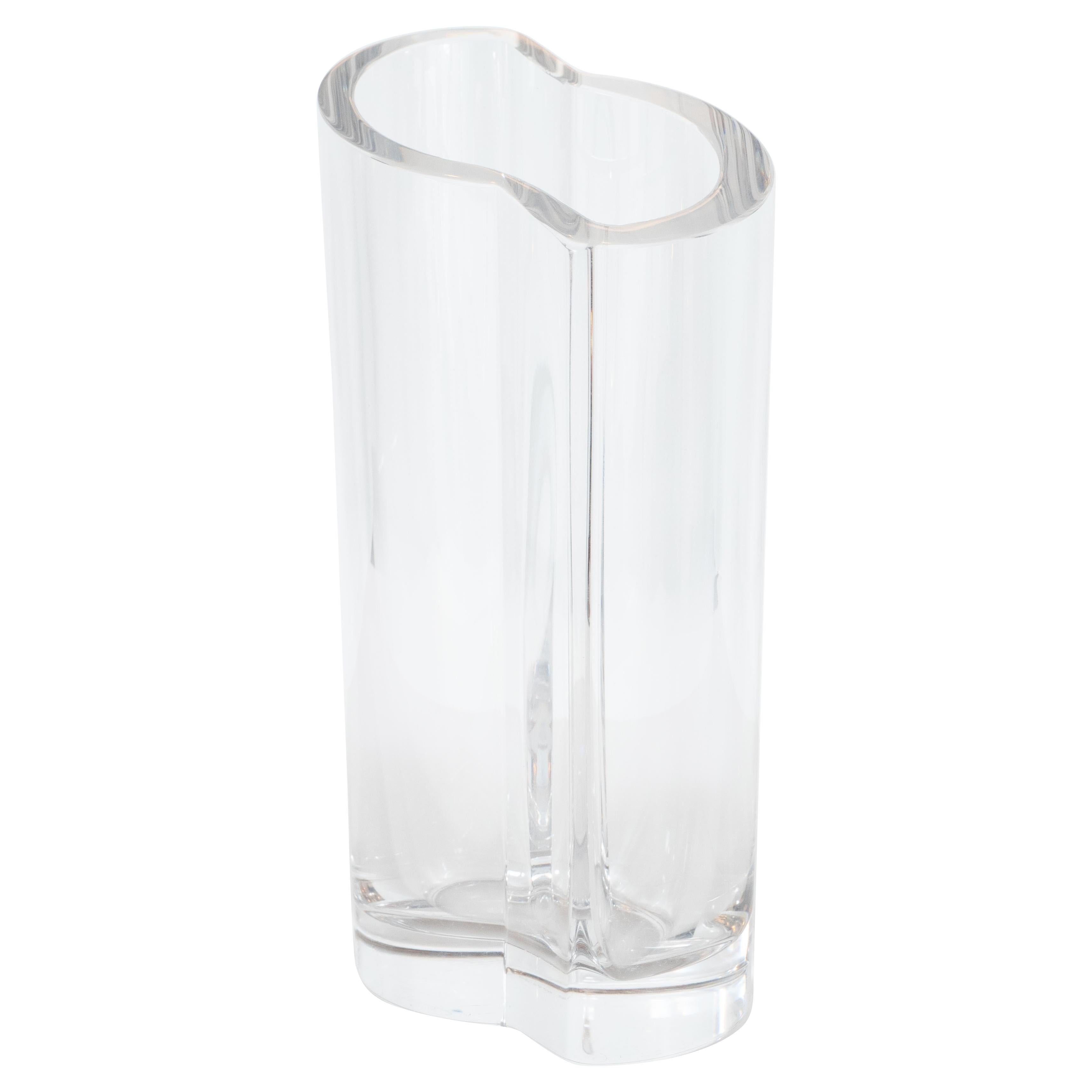 Ce vase élégant et discret de style moderne du milieu du siècle a été réalisé par le célèbre fabricant Orrefors, en Suède, vers 1960. Il se caractérise par des formes démilunes entrecroisées qui se rejoignent pour créer des plans rectangulaires de