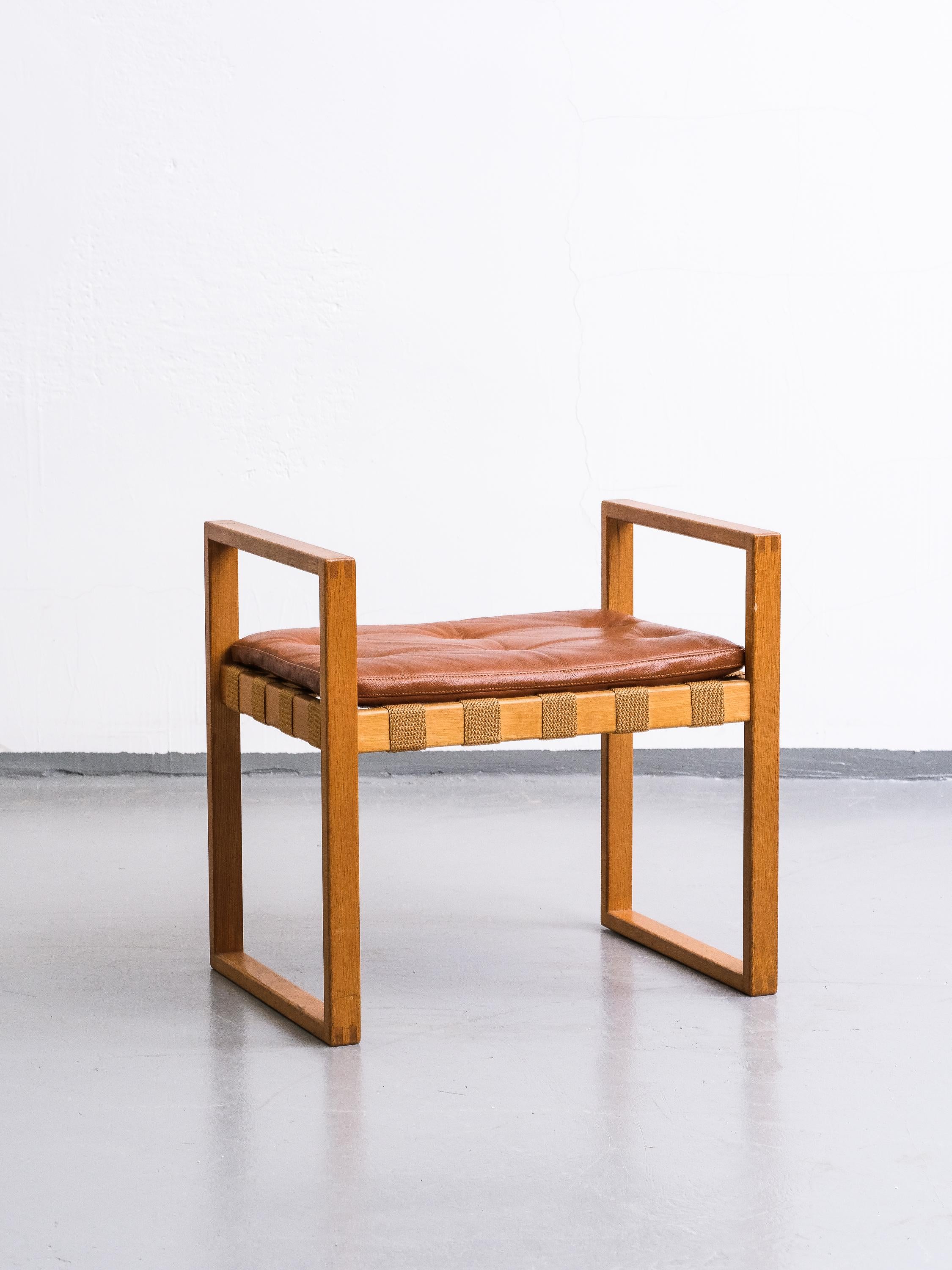 This stool was designed by Swedish designer Åke Fribyter and made in solid oak at Nybrofabriken, Fröseke. The details in the woodwork are in high quality. Seat cushion is new, made of cognac leather.