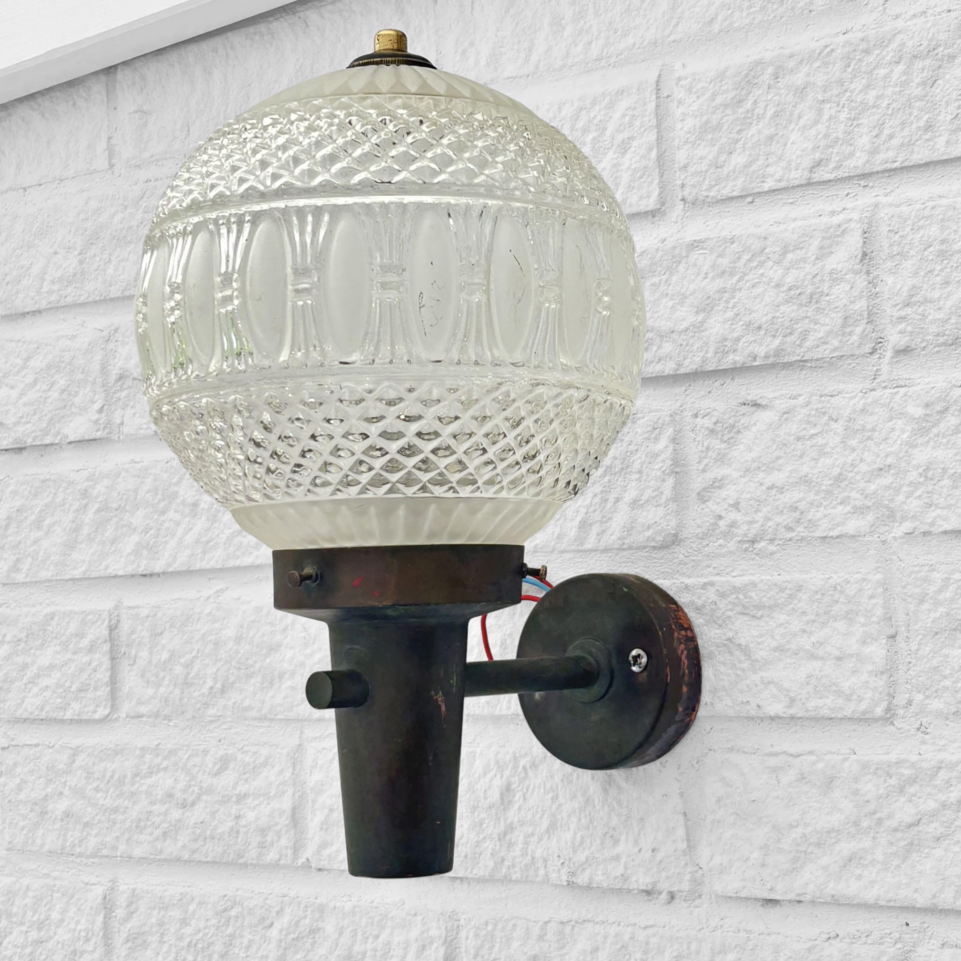 A Scandinavian outdoor façade lamp, produced by an unidentified Swedish manufacturer in the 1960s. Crafted from solid copper with a beautiful patina, it features a ball-shaped glass shade with an elegant relief pattern. Designed to be mounted