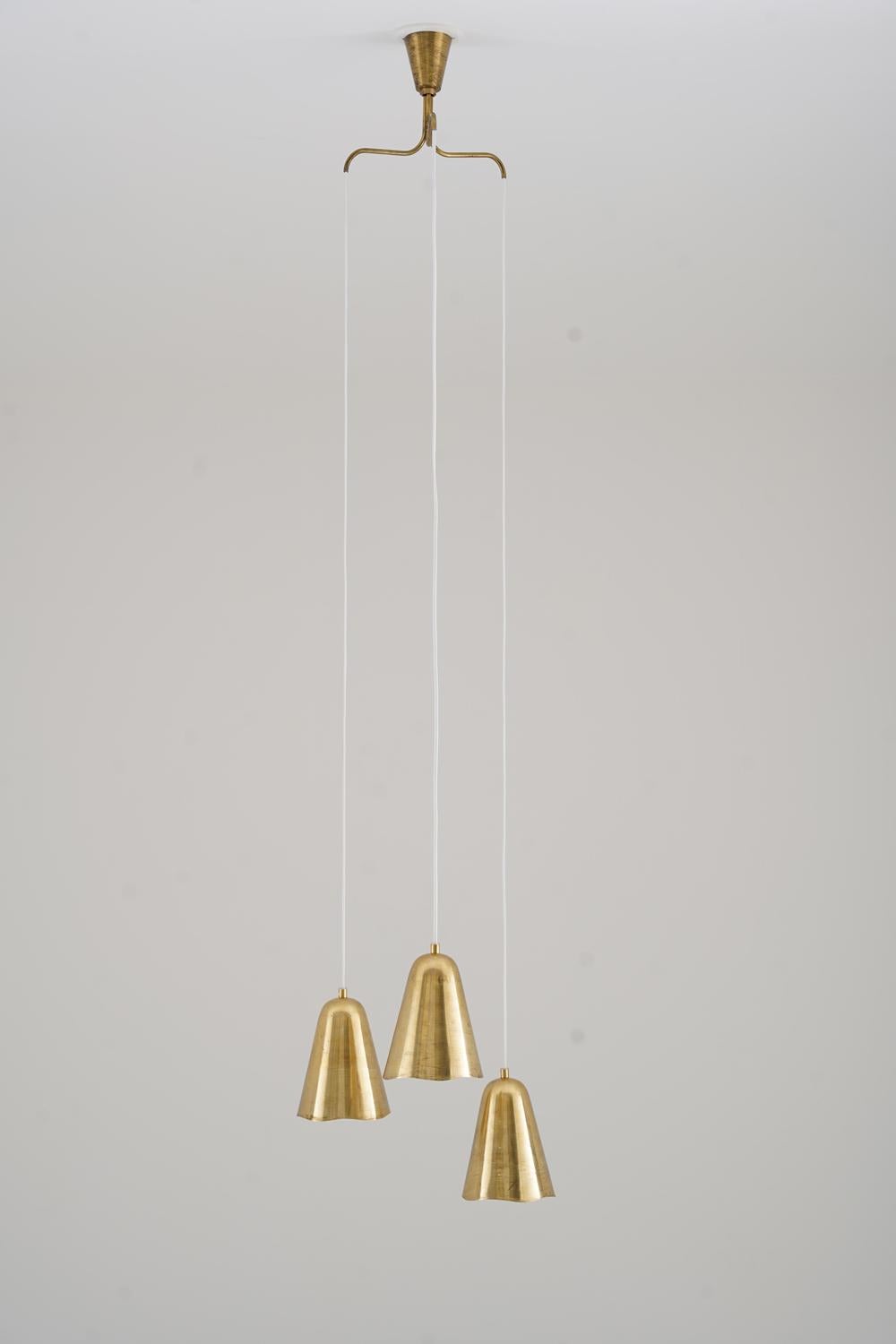 Lampada da soffitto della metà del secolo scorso, proveniente dalla Danimarca, con tre paralumi in ottone con bordi ondulati e sottili perforazioni. Sospeso ad altezze sfalsate da un baldacchino in ottone, proietta una luce calda e decorativa,