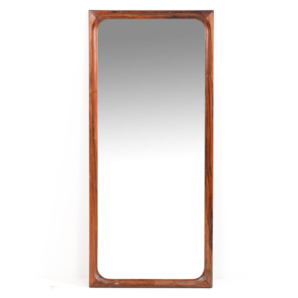 A fine quality wall mirror in heavy solid rosewood, featuring a gracefully curved and notched inner edge. Likely Swedish or Danish, in the manner of Aksel Kjersgaard.