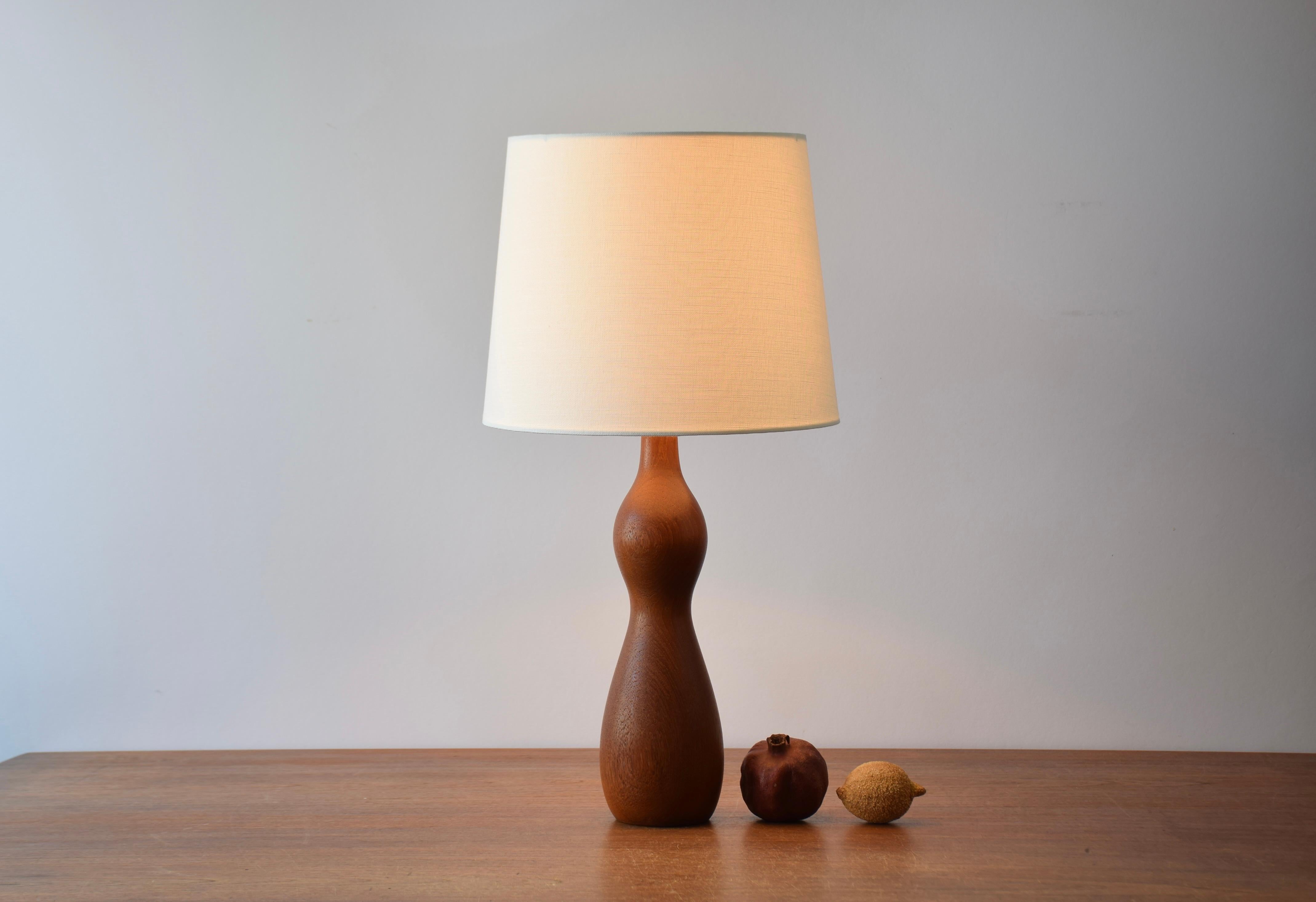 Original Scandinavian Mid-century table lamp made from turned teak.
Made circa 1960s.

The teak has a beautiful warm color and a lovely grain.

Included is a new lamp shade designed and made in Denmark. It is made of woven fabric with some