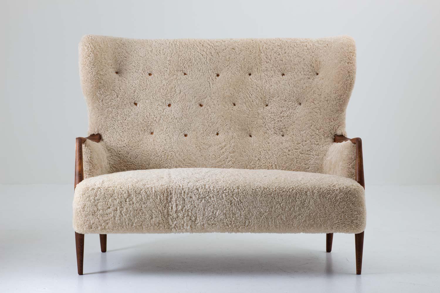 Stunning 2-seat sofa / loveseat produced in Denmark, circa 1940.
This wingback sofa is constructed with an impressive quality. The proportions and shapes are made with a great sense for design and the wooden details contribute to the exclusive