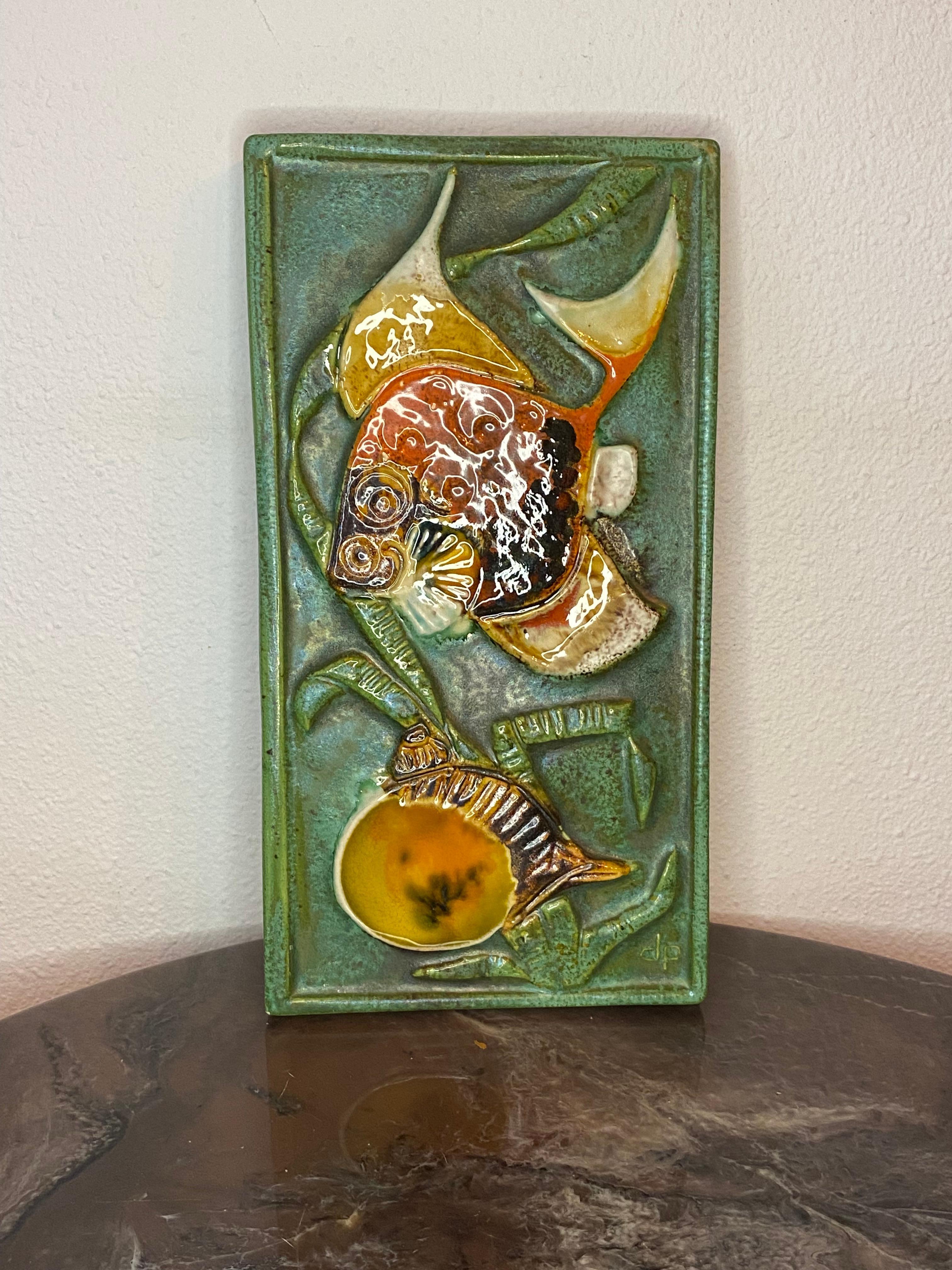 Nice stoneware wall plaque relief of a fish and a snail in bright colors by Tilgmans Pottery Sweden.

At the front there are the initials of the maker dp which stands for Danny Petrusson and on the bottom the wall plaque is stamped with the name of