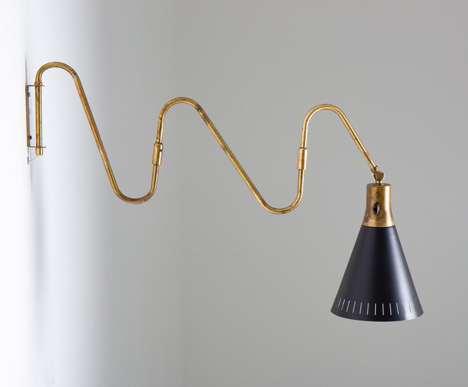Swivel arm wall lamp in brass with perforated black laquered metal shade. It features a three-piece swing arm and adjustable head.
Condition: Very good condition with beautiful patina on the brass. The shade has been repainted.