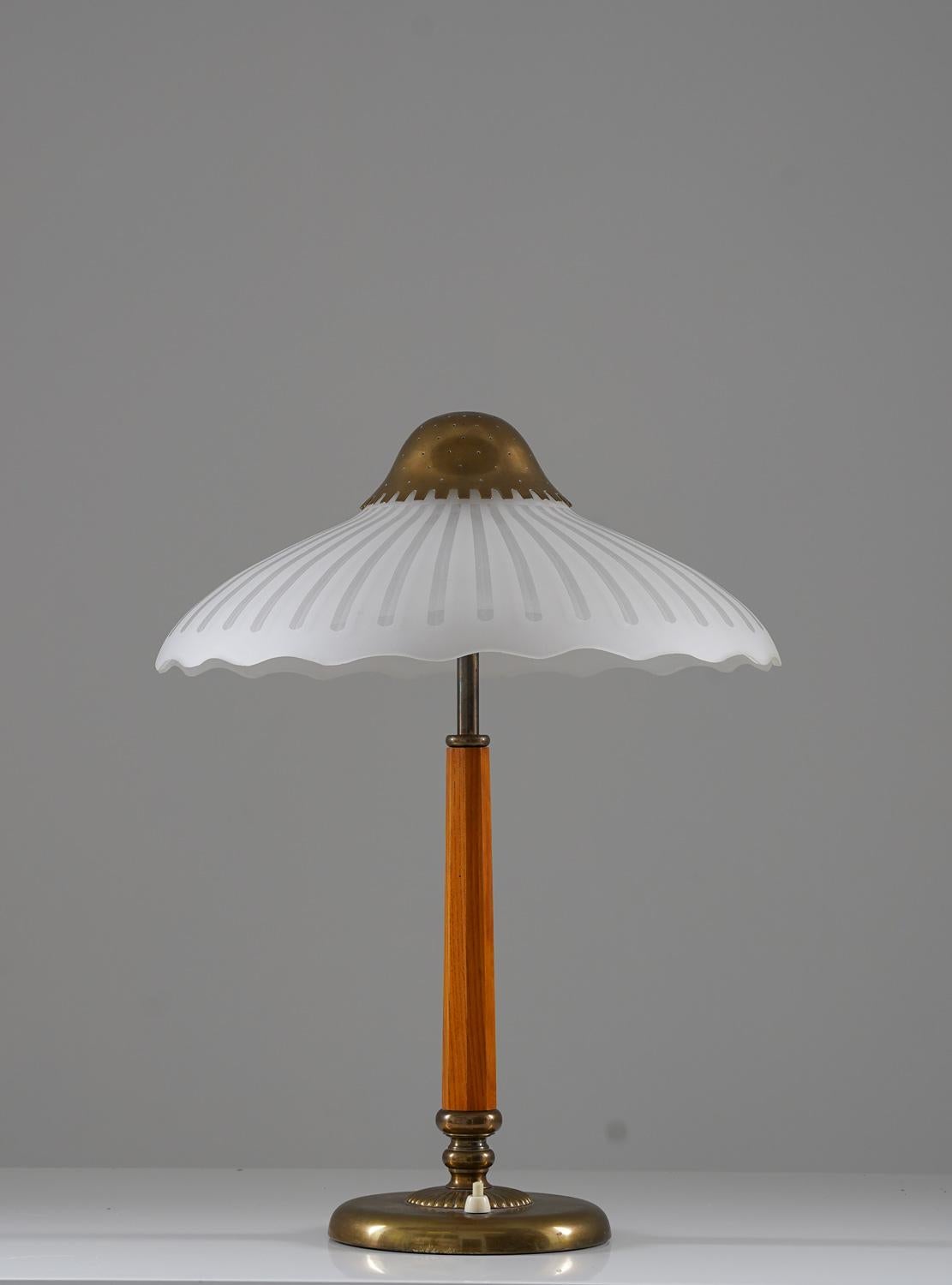 Very rare table lamp manufactured by ASEA (Sweden), 1940s. 
The lamp consists of a brass base with a wooden pole, supporting the shade of frosted glass. The shade is held in place by a perforated brass cover, giving a beautiful light.