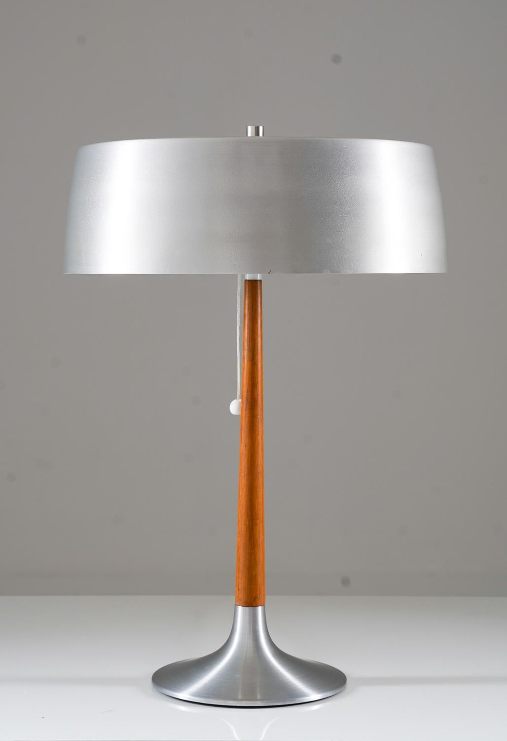 This table lamp by ASEA is a charming piece of lighting from the 1960s, hailing from Sweden. This lamp boasts a sleek and stylish design, crafted with brushed aluminum and teak. 

In terms of its condition, the lamp is in very good condition, with