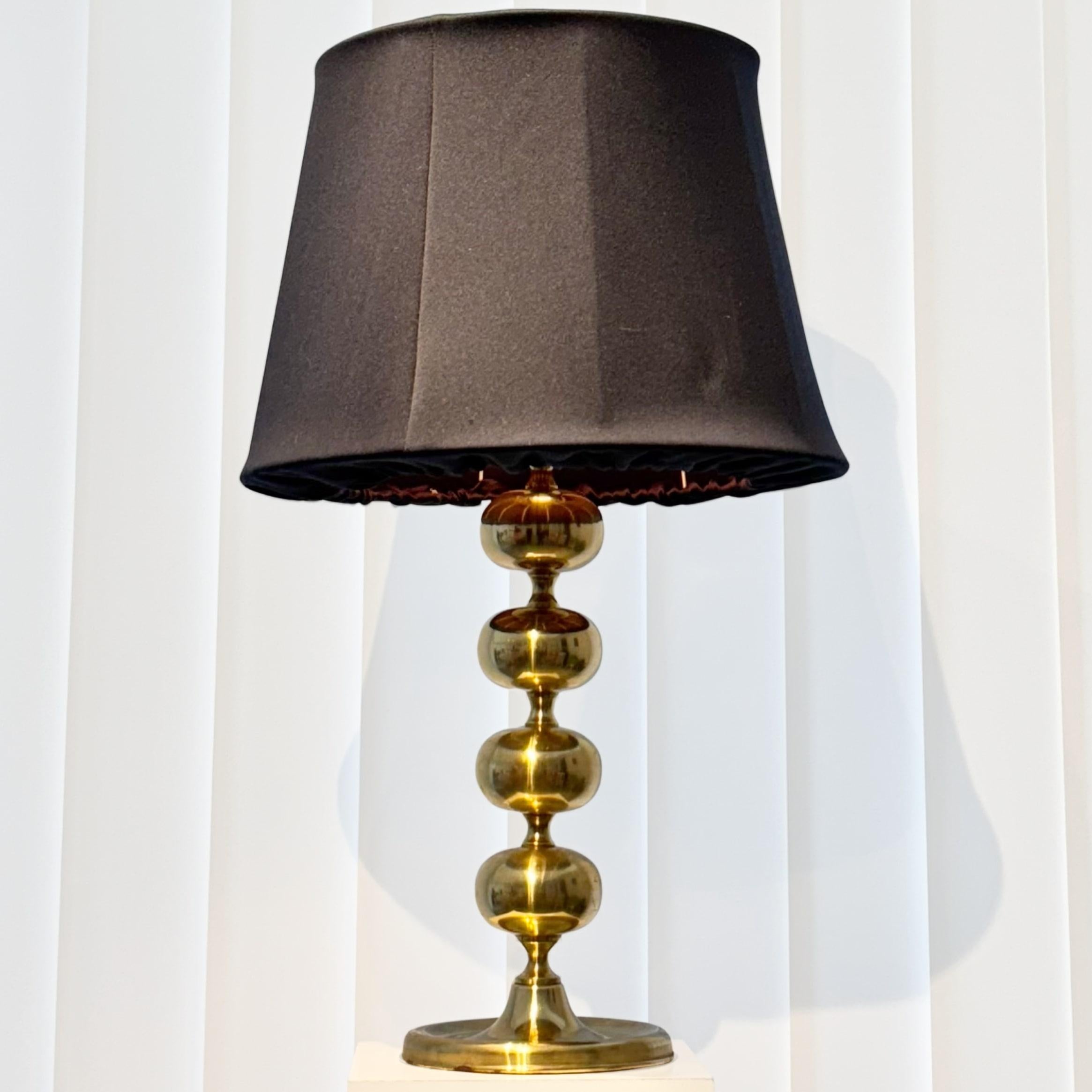 Élégante lampe de table du milieu du siècle, modèle GMA 705, fabriquée en laiton avec un design sculptural comprenant quatre sphères en laiton gracieusement disposées. Elle comprend une douille E27 standard au sommet, associée à un grand abat-jour