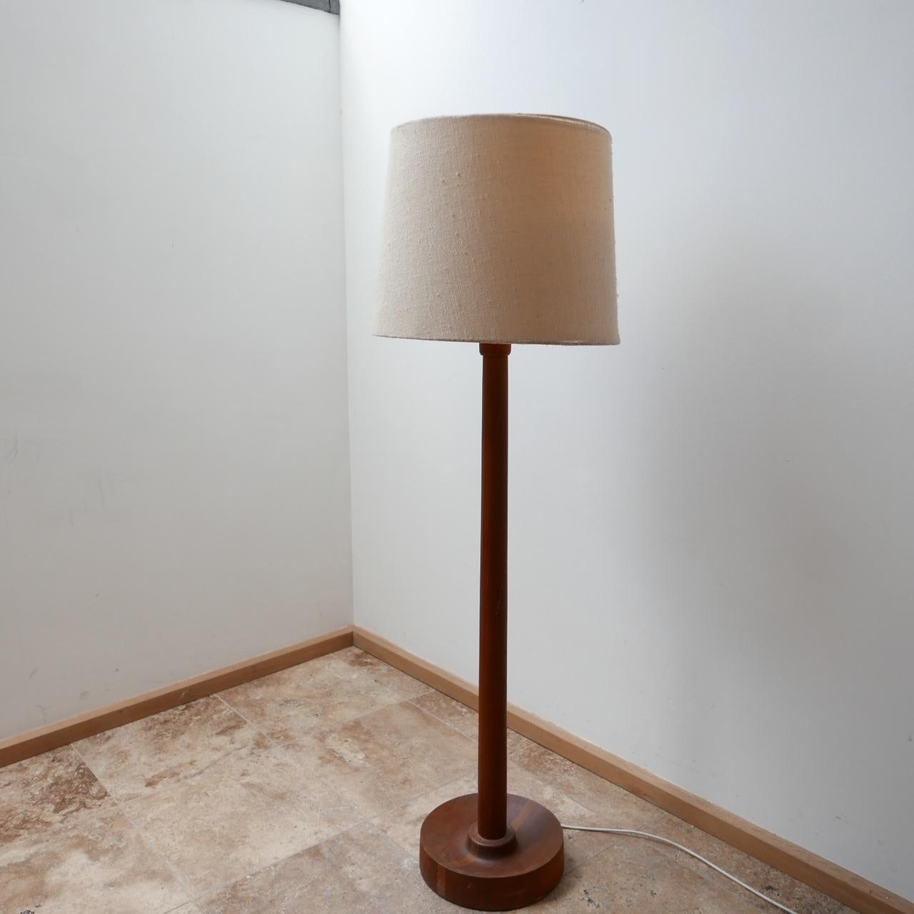 An elegant mid-century teak floor lamp. 

Denmark, c1970s. 

Original shade was retained but there is wear commensurate with age so may want changing. 

Dimensions: 130 height x 31 diameter without shade, 142 height x 45 diameter with shade,