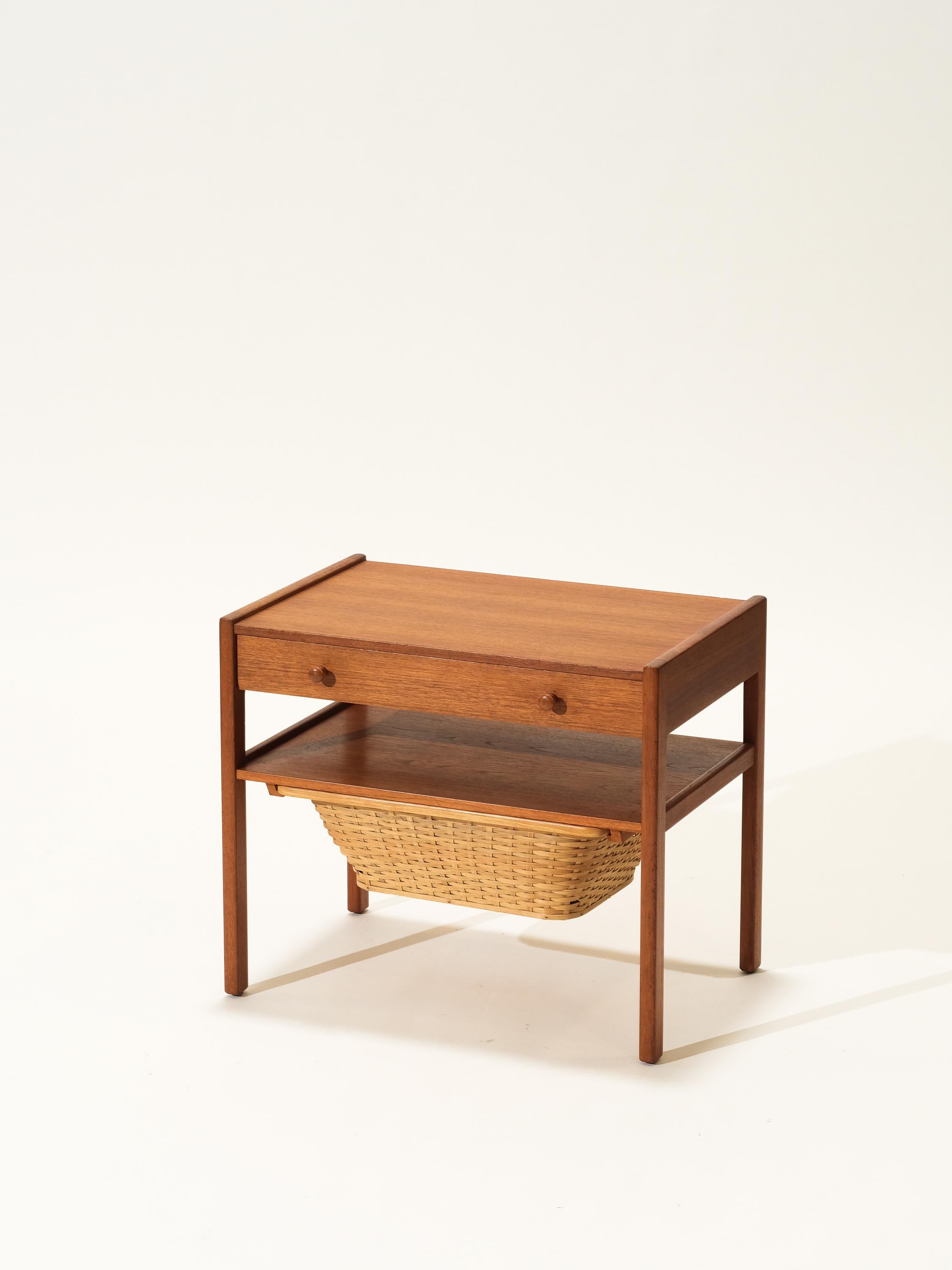 Vintage Scandinavian modern side table features a pull-out woven rattan basket and a large drawer. Sleek and sturdy design, beautiful teak wood grain and a finished back. This piece can be used as a sewing table, end table or a decorative piece.