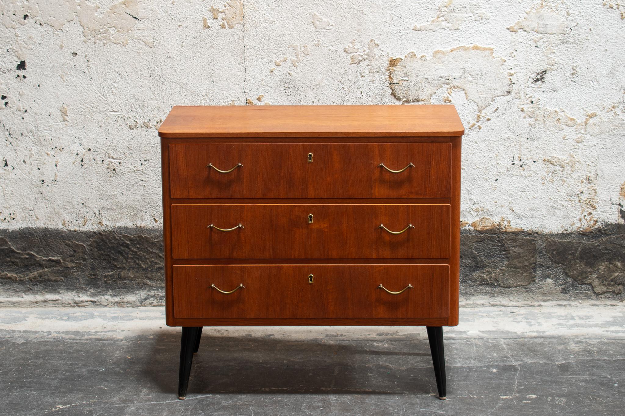 Three drawer teak chest on round black tapered legs with original brass hardware.

A great piece to store your bedding or clothes. A handsome piece of furniture in any room.