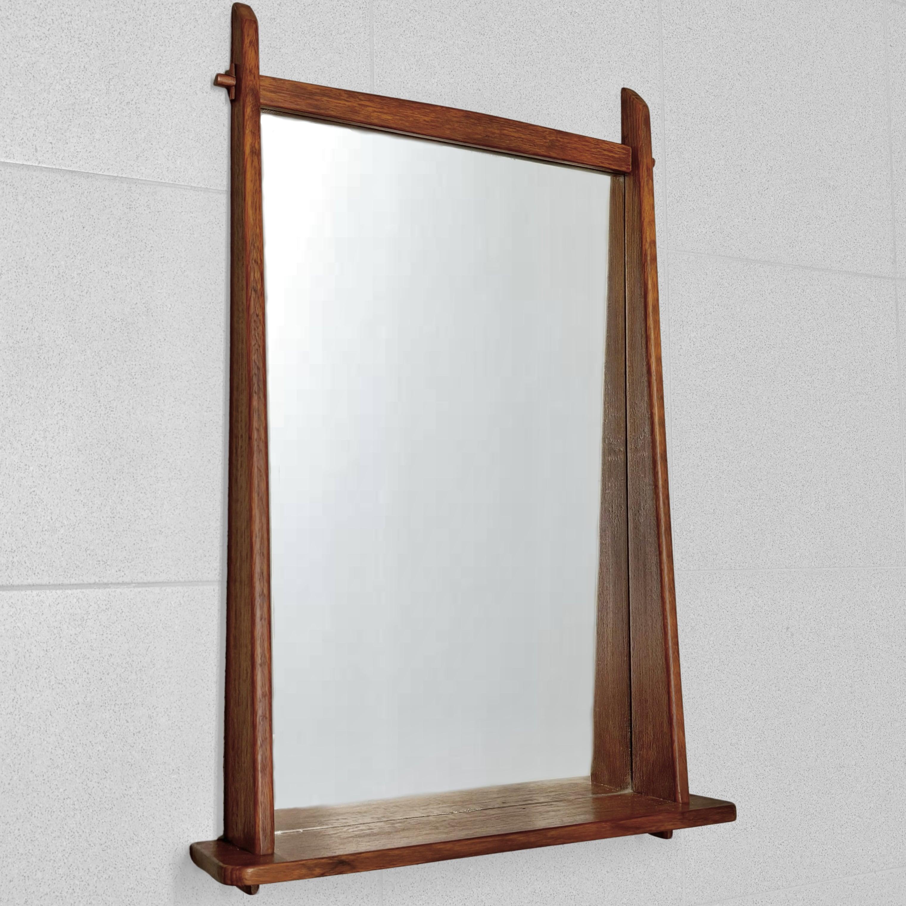 Miroir mural moderne du milieu du siècle, produit par un fabricant suédois non identifié dans les années 1950. Fabriqué en teck, il est doté d'un miroir rectangulaire et d'une étagère pratique pour les petits objets. Des joints décoratifs soulignent