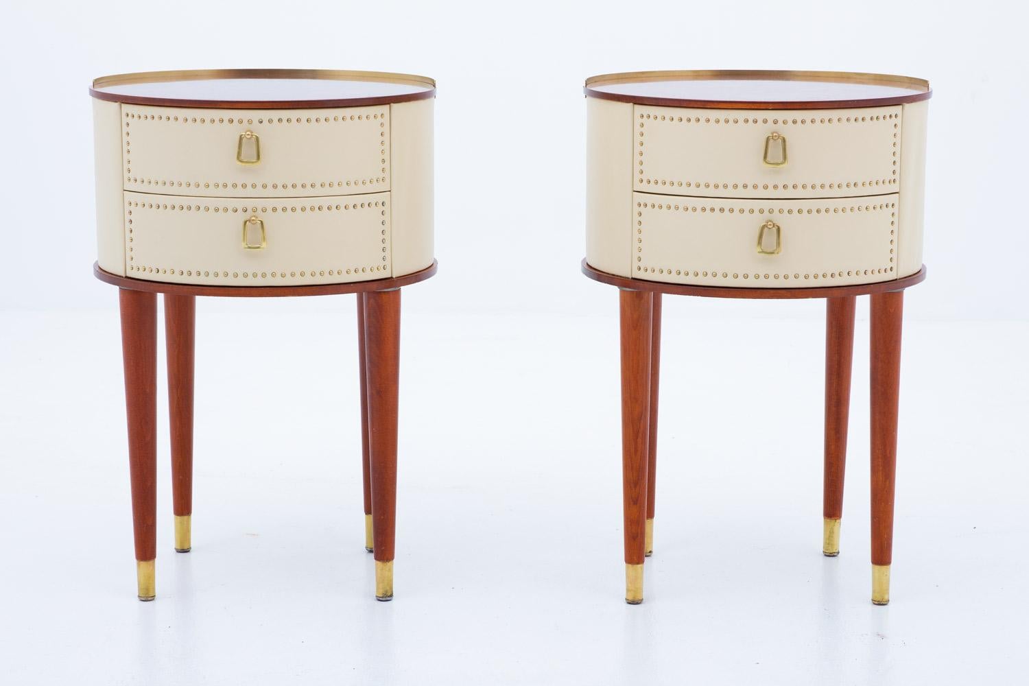 Midcentury bedside tables designed by Halvdan Pettersson for Tibro Möbelfabrik, circa 1940.
These round bedside tables are covered in cream white faux leather with brass details. The tabletop is made of mahogany and the legs of stained