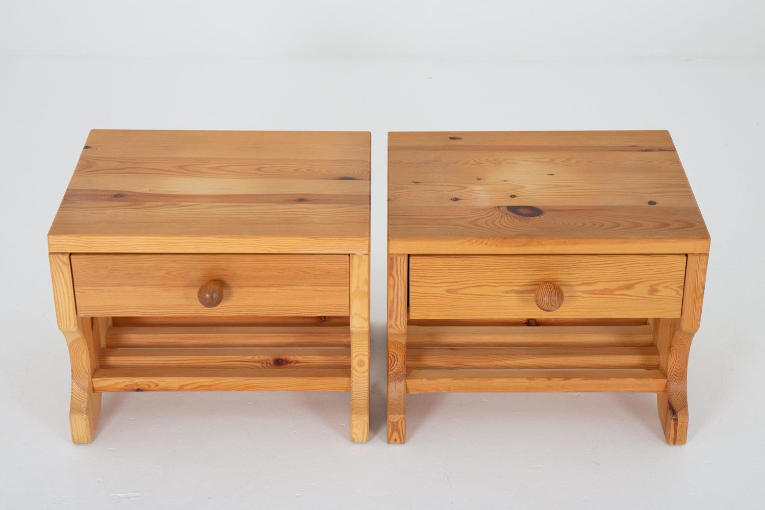 A pair of bedside tables by Stig Höglunds Träsvarveri, 1970s.
These bedside tables are made of solid pine with great details, such as the visible joinery and the round handles.

Condition: Good original condition. Light signs of age and use, a