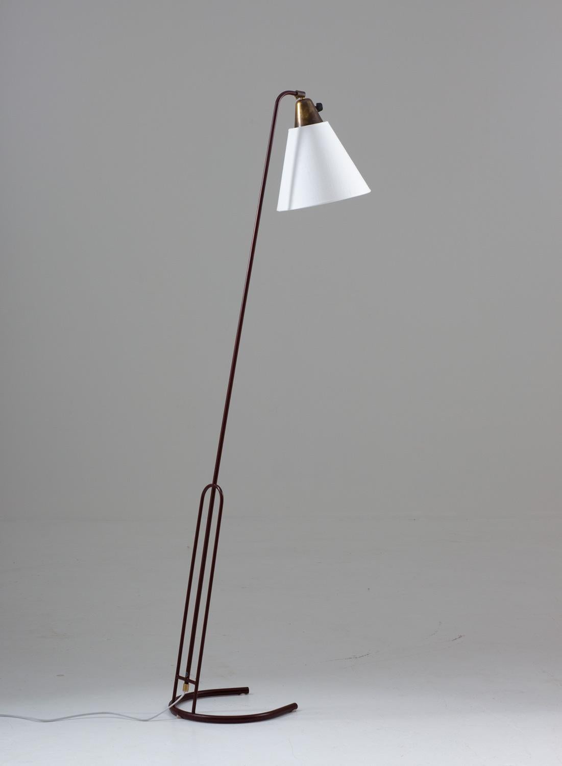 Lovely floor lamp in brass and metal, produced in Sweden, circa 1950.
This lamp consists of a thin wine-red metal pole, supporting the adjustable lamp shade. The lamp stands on a elegant horse shoe-shaped metal base. 
Condition: Very good original