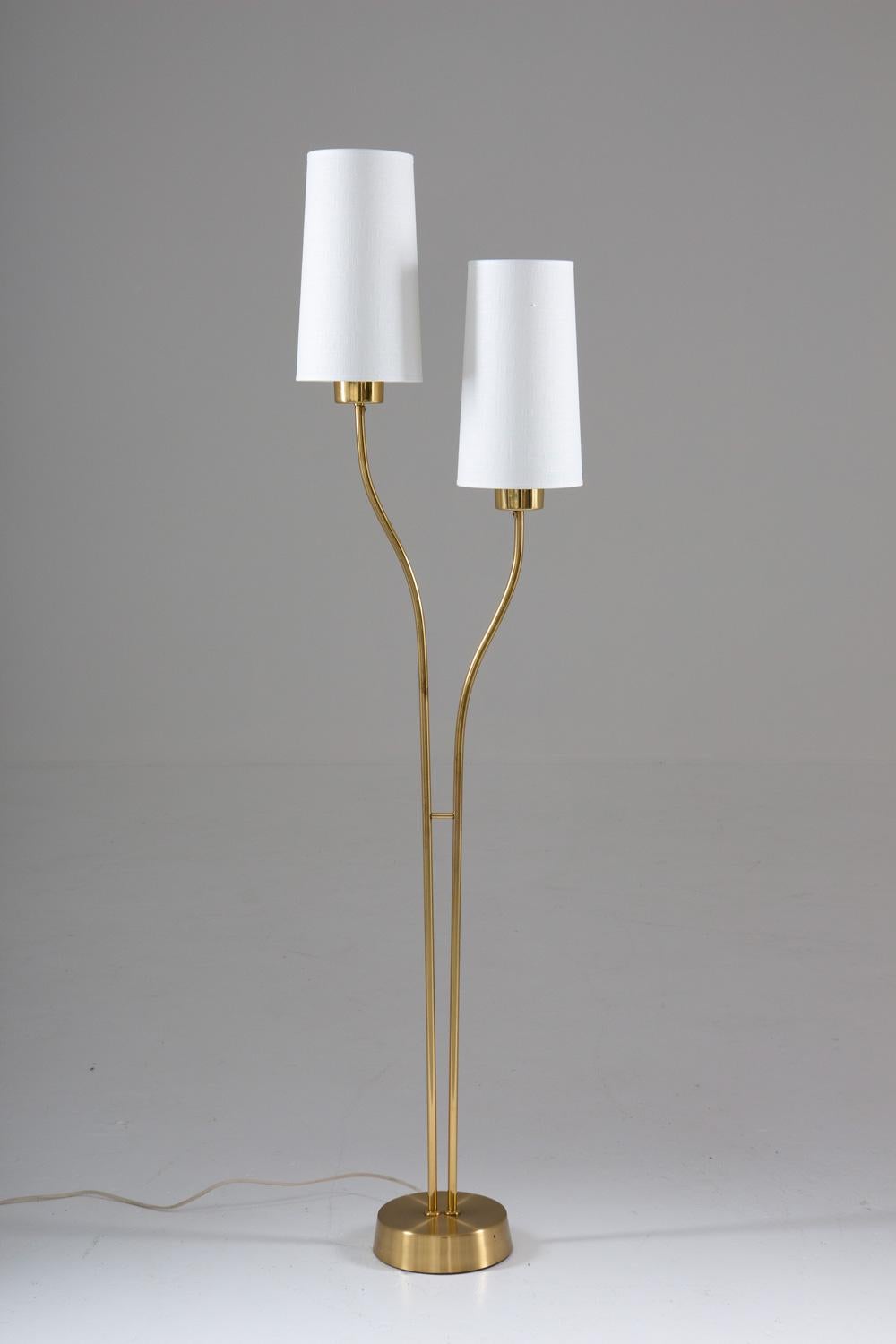 Floor lamp model 5738 EOS, Sweden 1950s.
Beautiful floor lamp, consisting of two organically-shaped brass rods, each holding a cone-shaped fabric shade. The rods are resting on a heavy brass-covered foot. 

Condition: Very good original