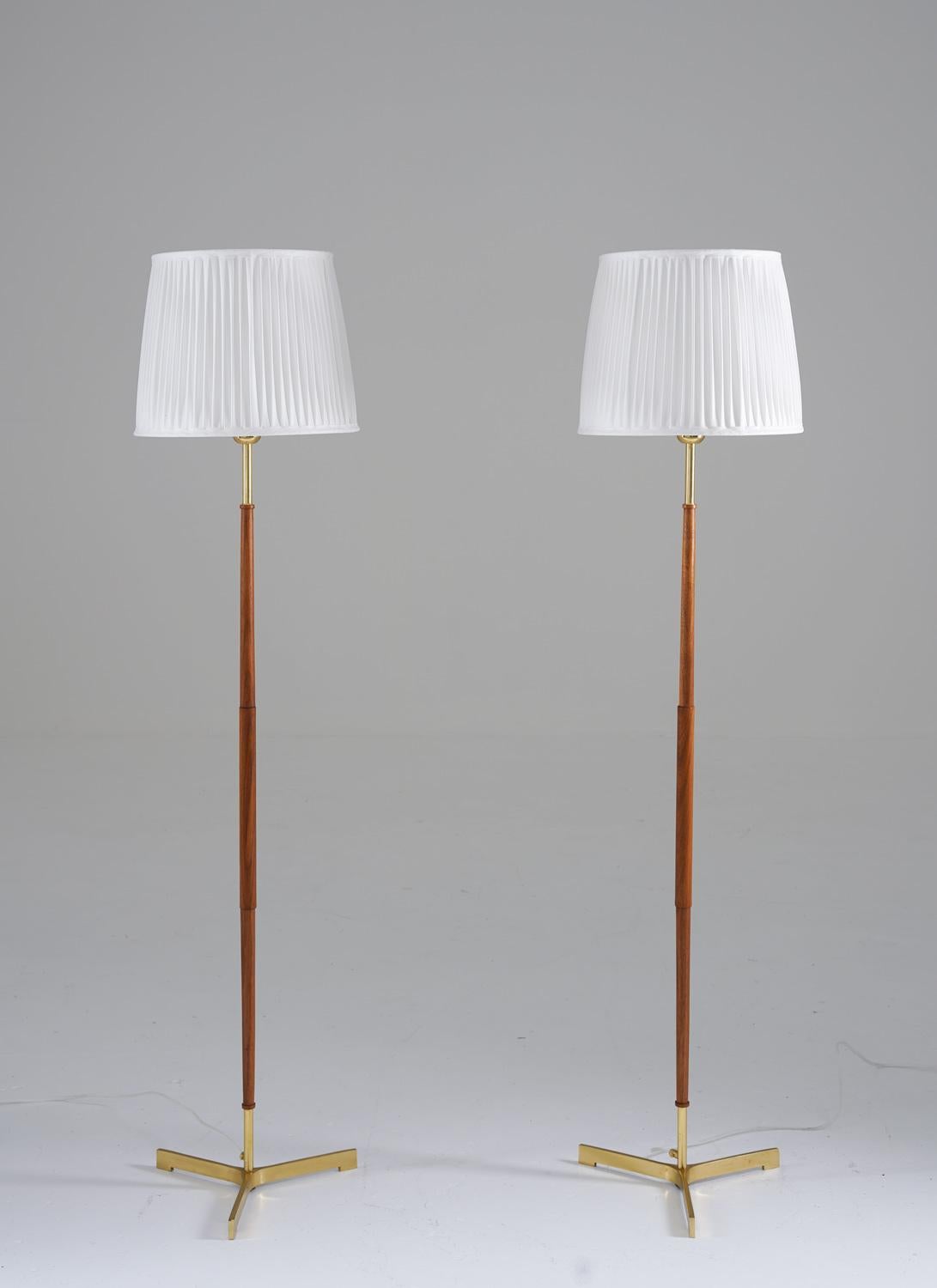 Scandinavian midcentury tripod floor lamps in brass and wood, manufactured in Sweden, 1960s.
These lamps consist of a wood and brass base, resting on a tripod foot in solid brass. They come with new hand-pleated shades. 

Condition: Very good