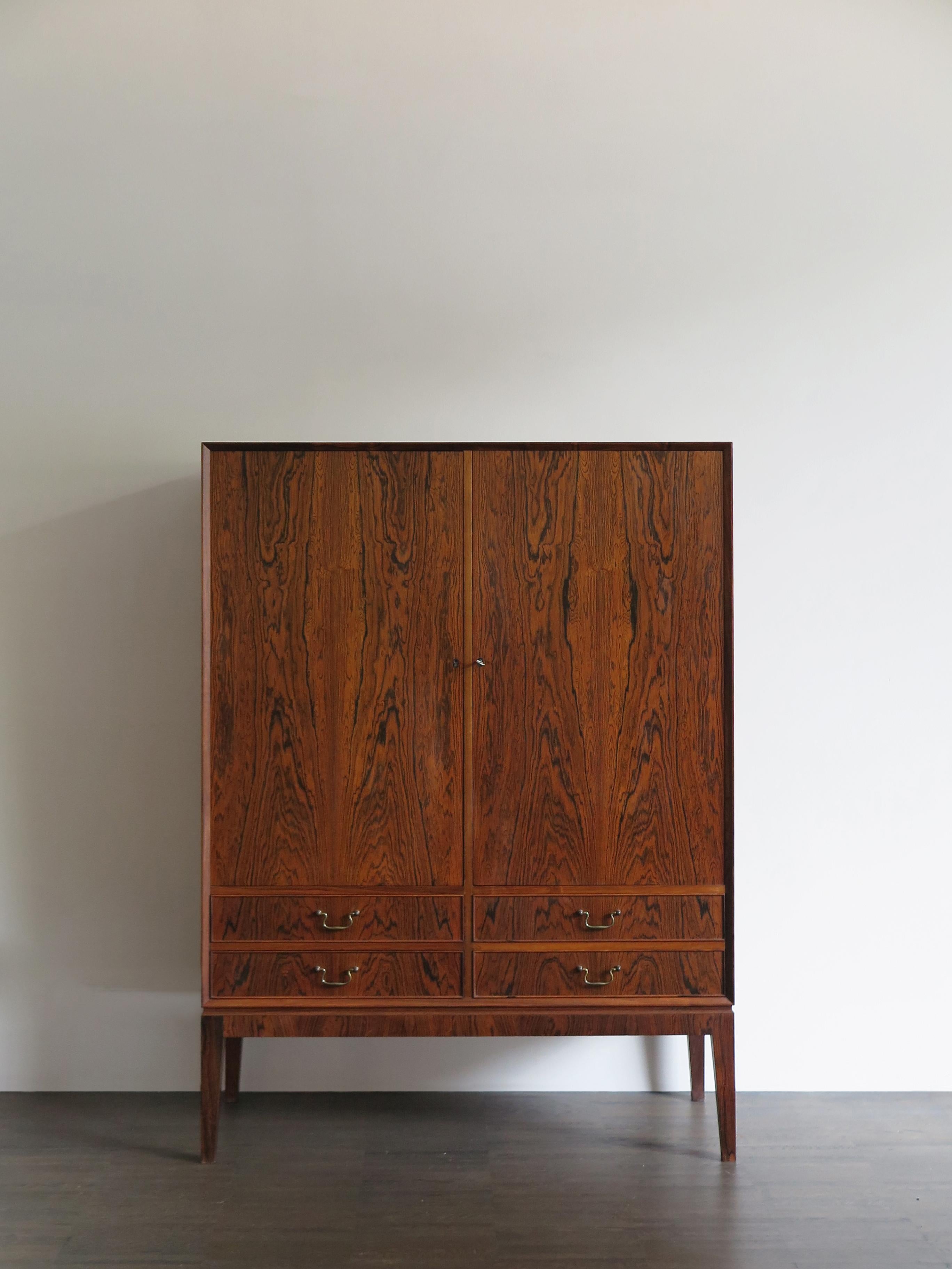 Scandinavian Mid-Century Modern design rosewood cabinet produced by O. Bank Larsen Møbelfabrik with fours drawers with brass handles and two doors, manufacturer’s adhesive label inside a drawer, Denmark 1960s.
Very clean and contemporary line and
