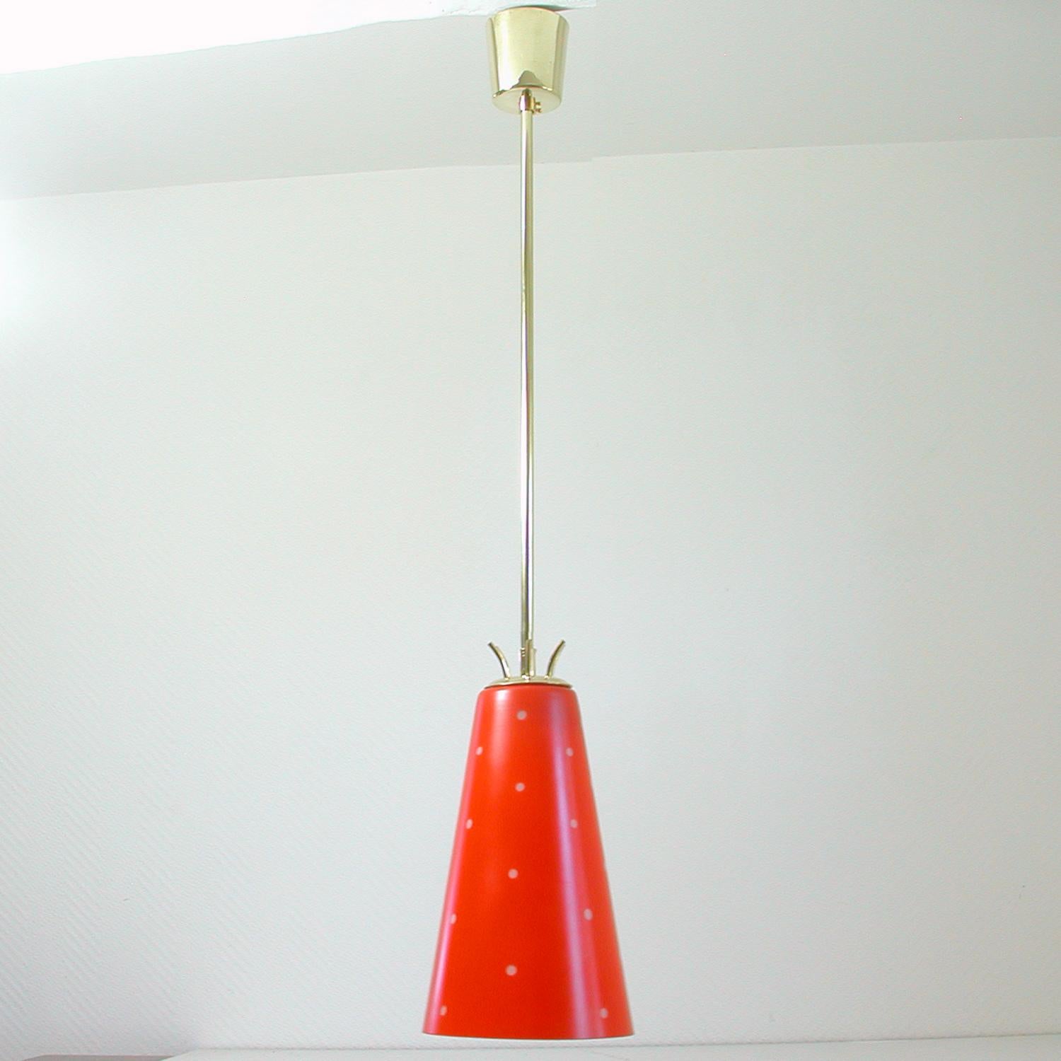 This unusual pendant was manufactured in Sweden in the 1950s. It is made of brass and has got a red and white (dotted) opal glass lampshade. I would call the red color tomato.

Condition is very good and the lamp is in full working order