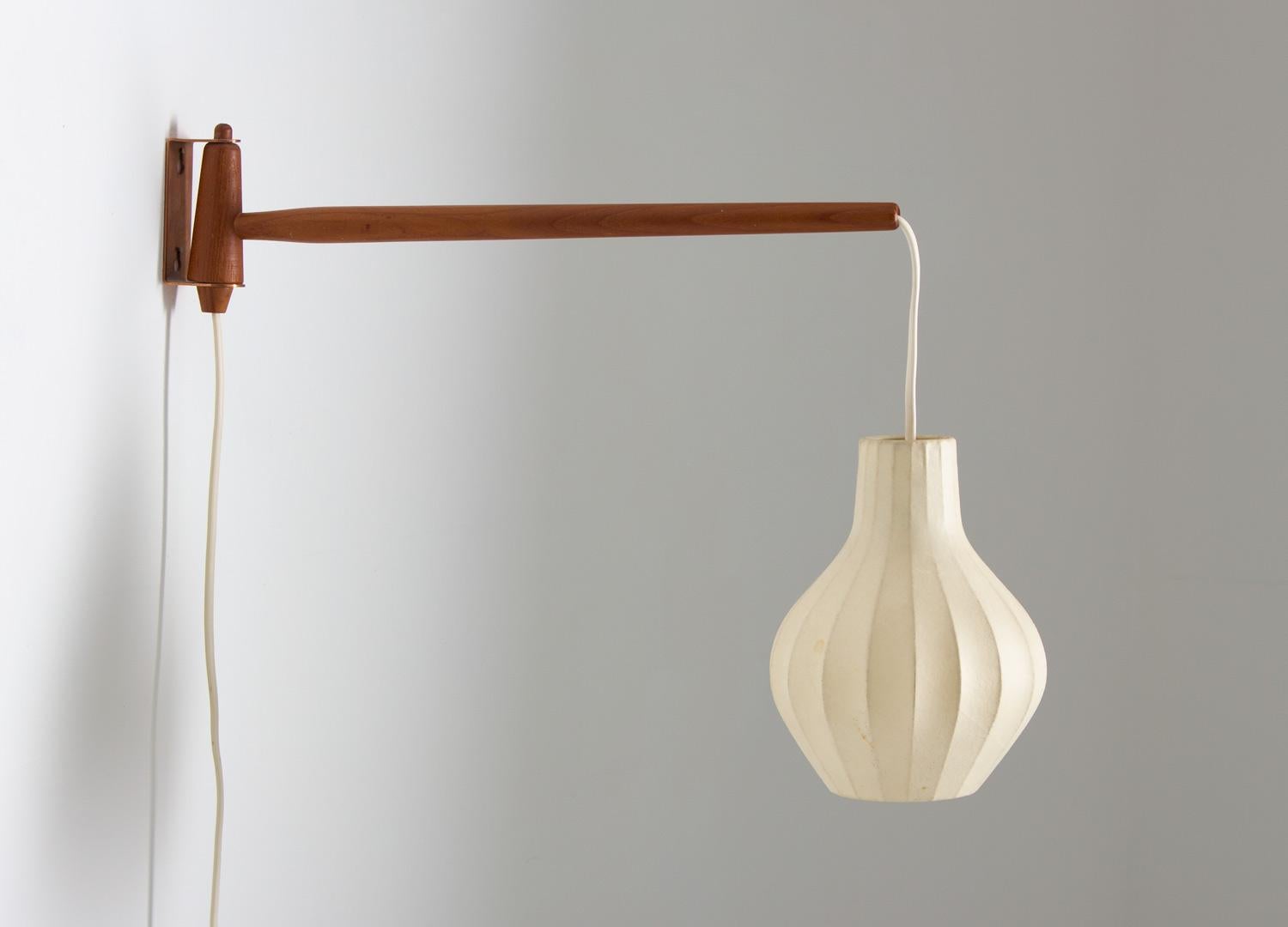 Scandinavian midcentury swivel wall lamp by Hans-Agne Jakobsson.
This early and rare lamp comes with its original cocoon shade. The shade is held by a teak stick, with the wire hidden inside. The lamp is marked 