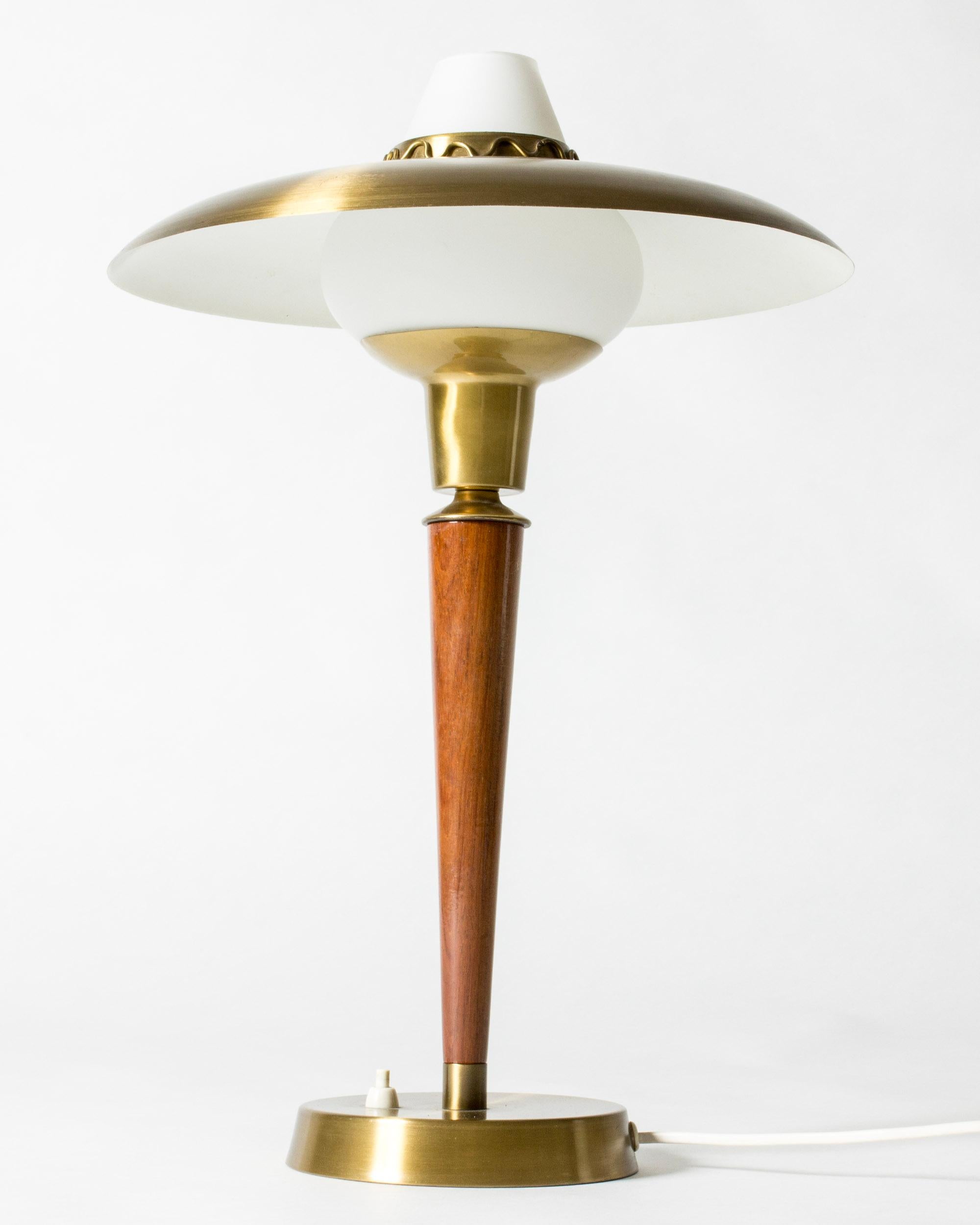 Lampe de table élégante et ludique de Hans-Agne Agnes, réalisée en laiton avec une tige en teck et un abat-jour en verre opalin. Vague décorative autour du sommet de l'abat-jour.