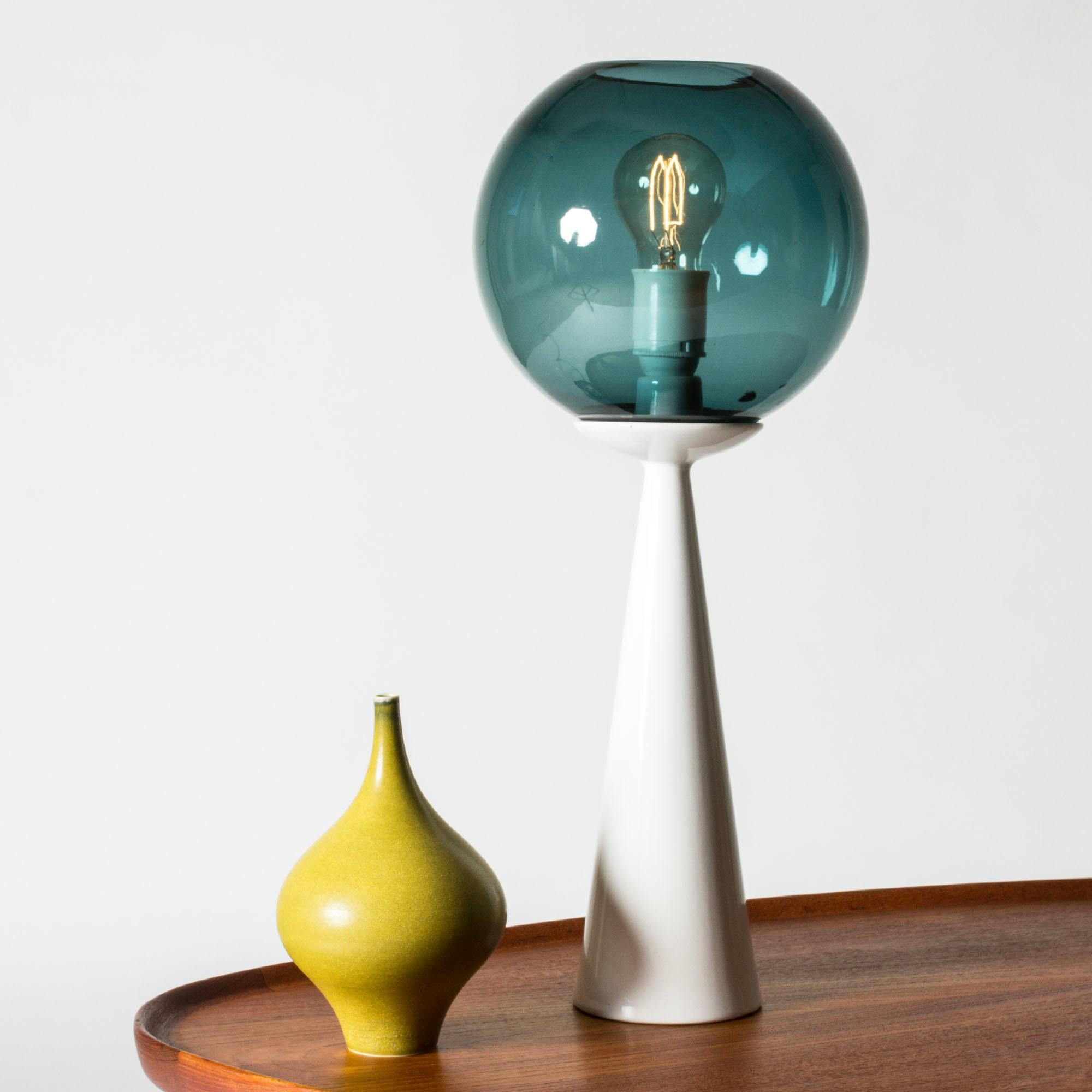 Striking table lamp by Hans-Agne Jakobsson, with a streamlined white ceramic base and round glass shade in a petrol blue nuance.