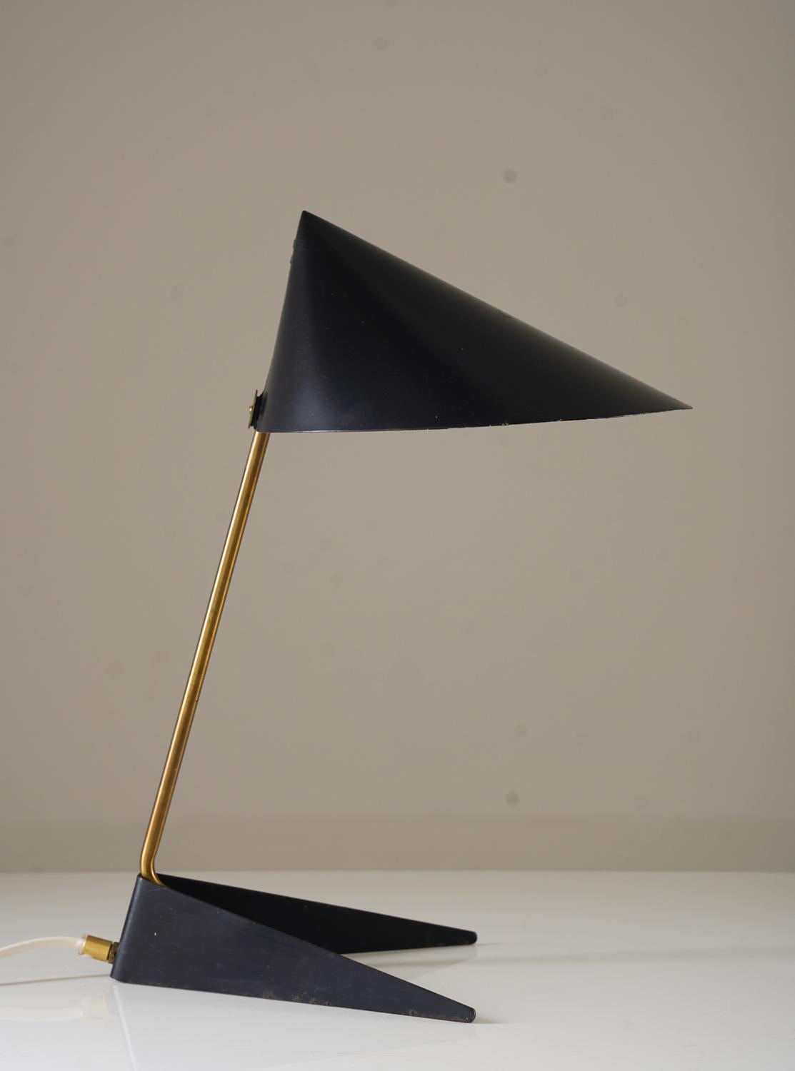 This table lamp, designed by Svend Aage Holm Sørensen and manufactured by ASEA, embodies the elegance of mid-century modern design. Its striking black conical shade, paired with a sleek brass stem and angular black base, creates a minimalist yet