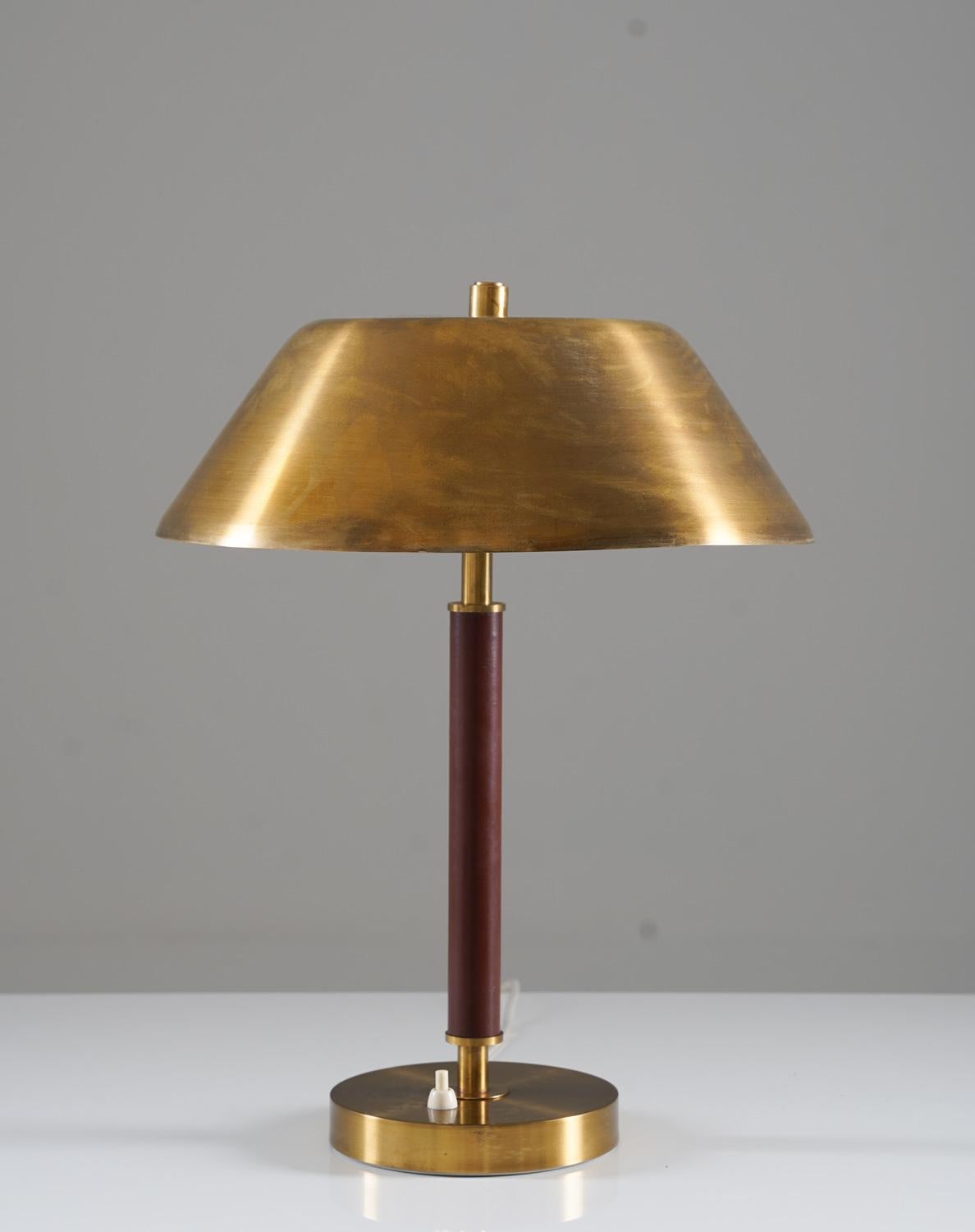 Beautiful table lamp manufactured by Falkenbergs Belysning, circa 1960.
This lamp is made of brass with a leather-covered base.

Condition: Good original condition with beautiful patina on the brass. The shade is slightly askew and has a minor