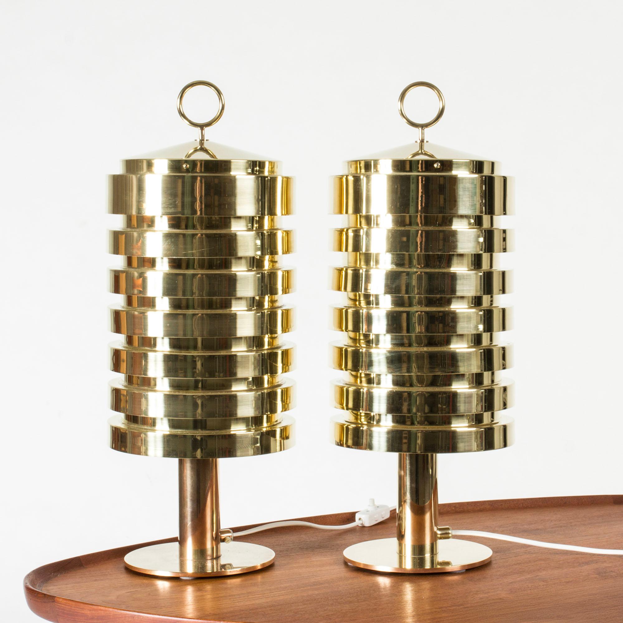 Pair of rare, amazing brass table lamps by Hans-Agne Jakobsson, model #B99. Large design in a cylinder form with decorative hoops on the tops. Brass lamellas are stacked in a tight design letting the light out with a warm glow.