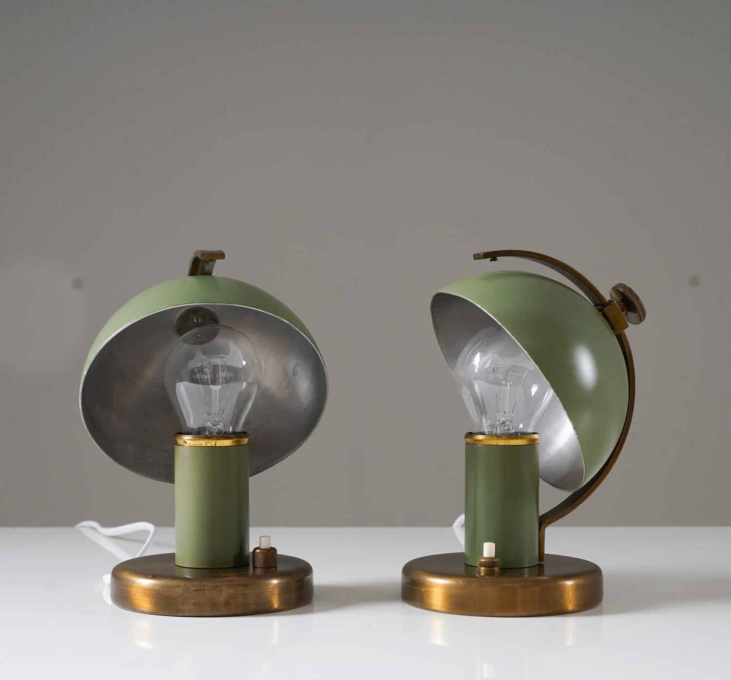 Introducing a pair of petite functionalist table or wall lamps, designed by Erik Tidstrand for Nordiska Kompaniet (NK) in the 1930s. These lamps are a stunning example of functionalist design, with their adjustable green metal reflectors held by a