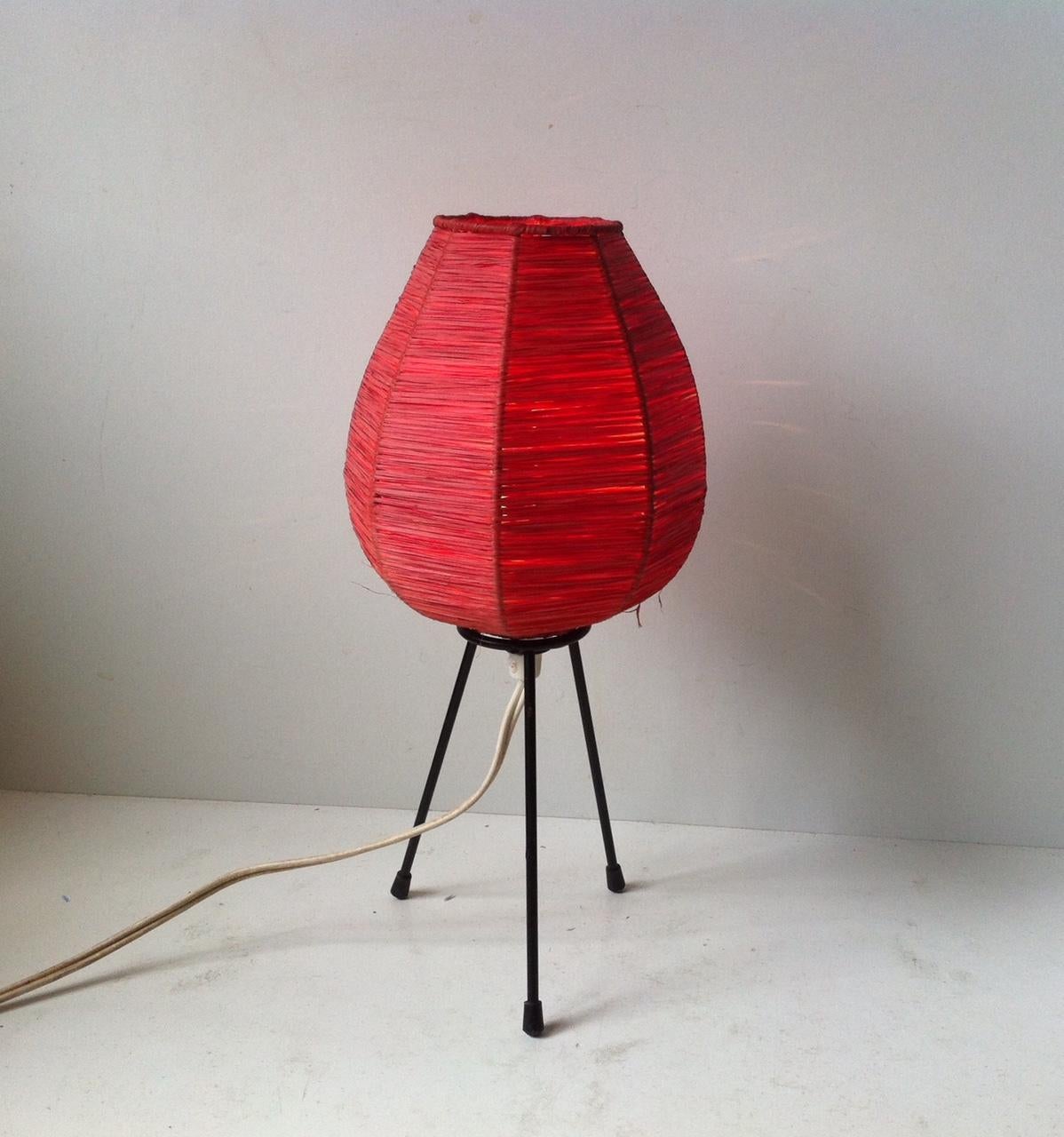 Small and light tri stand table light composed of a red paper thread shade and lacquered steel body. It was made in Scandinavia during the 1970s in a style reminiscent of Isamu Noguchi.