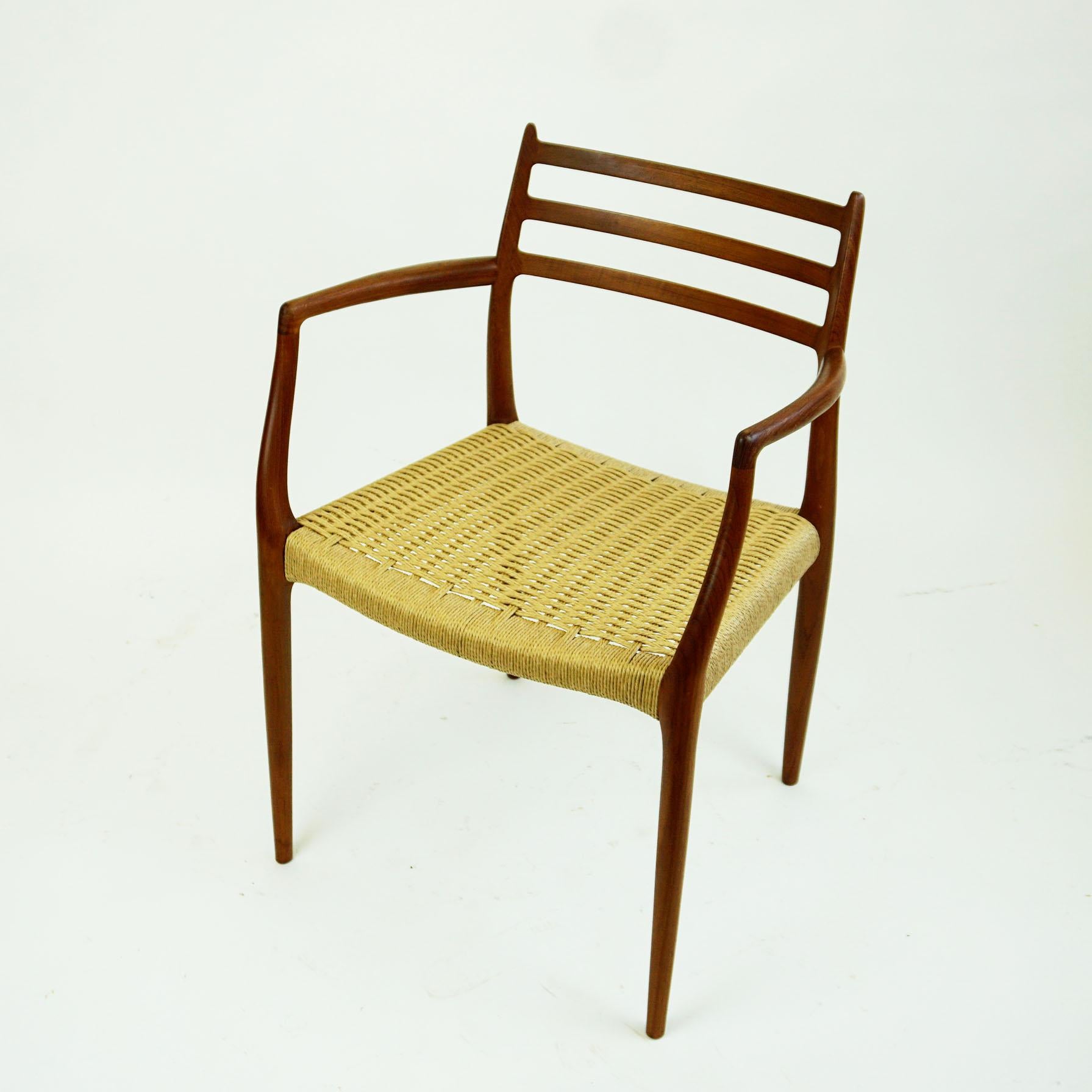 Rare and iconic Scandinavian Modern Mod. 62 teak dining armchair designed by Niels Otto Moller for his own company: J.L. Moller Mobelfabrik in Denmark, 1962. This piece is in excellent condition and features a newly woven papercord seat. Danish
