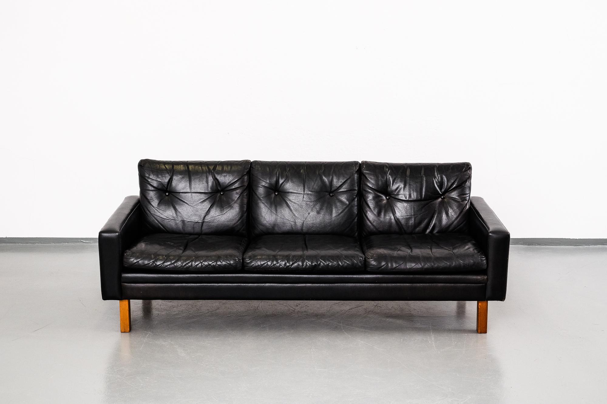 Three-seat sofa in black leather and with teak legs. Scandinavian design from the 1960s. The sofa is in great vintage condition.