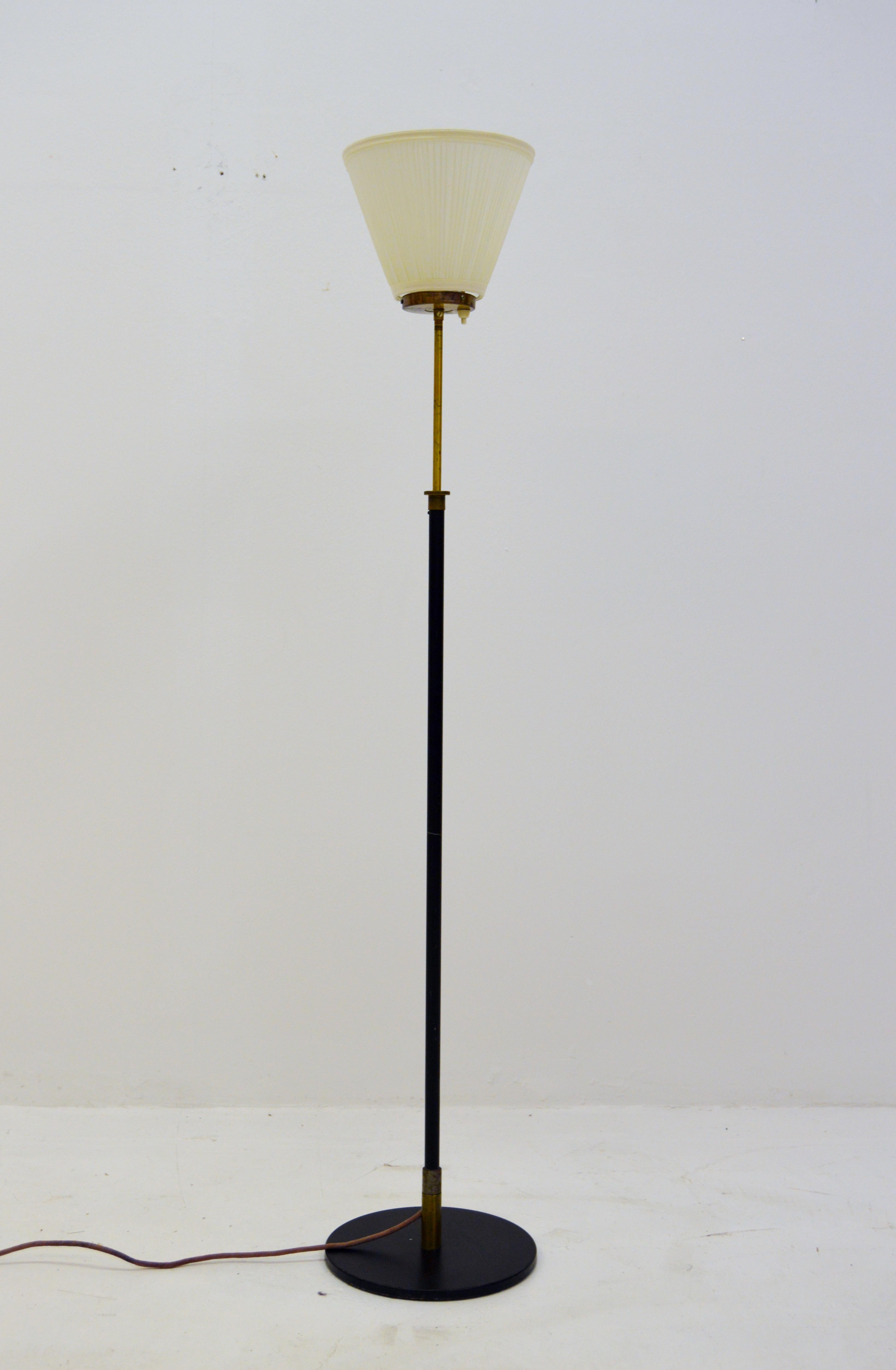 Unusual floor lamp with black metal bar and elegant brass details. Uplight with adjustable height 110 cm-160 cm circa.
Lampshade made of fabric in top, with a black metal foot and metal bar. The cord has since the photo was taken been replaced with