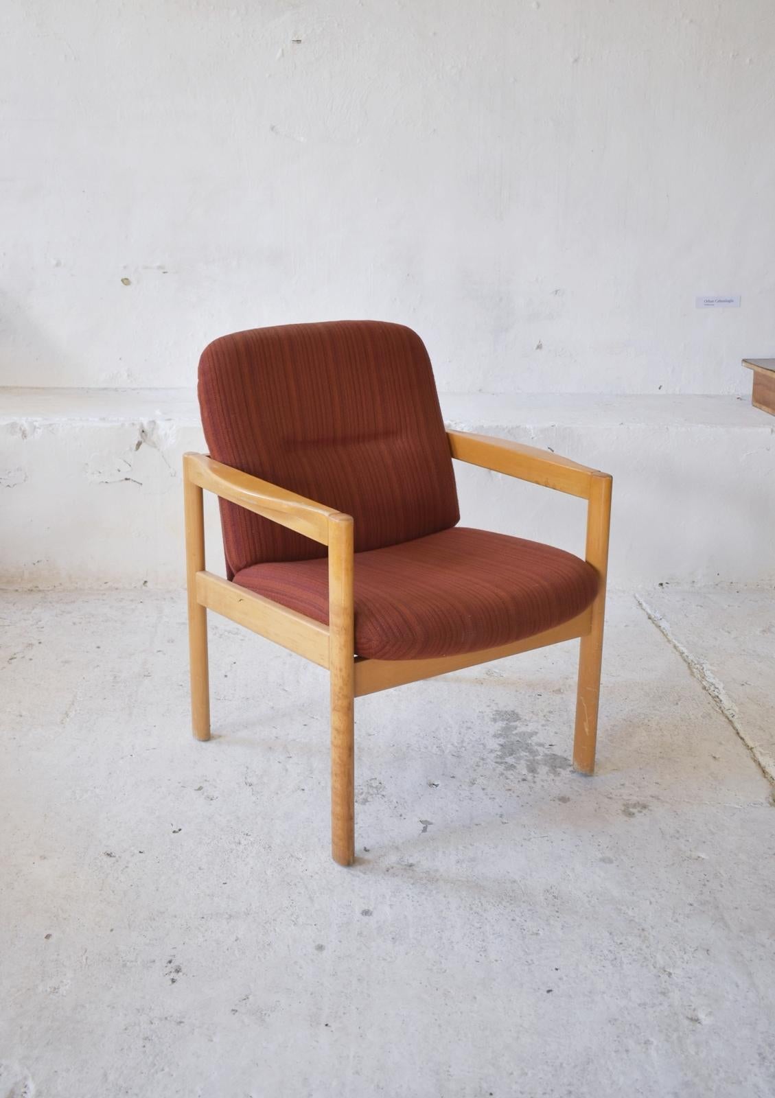 Ce fauteuil des années 1970 est une pièce classique et intemporelle, fabriquée avec un cadre en bois et tapissée d'un tissu côtelé aux tons rouge bordeaux. Son design épuré et minimaliste rappelle les traditions du mobilier scandinave, ce qui en