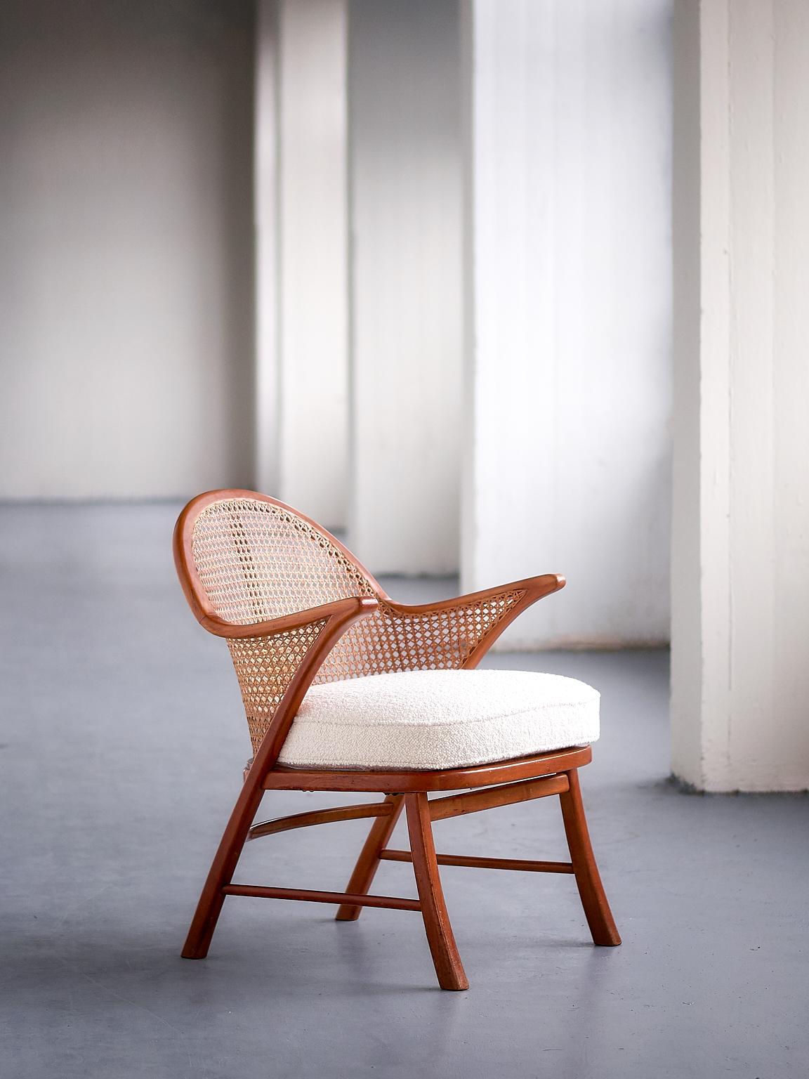 This elegant armchair was produced in Denmark in the late 1950s. The striking solid beech frame is marked by its curved legs, two slats on the sides and one rear slat. The curved backrest of the chair is executed in a French cane. The original