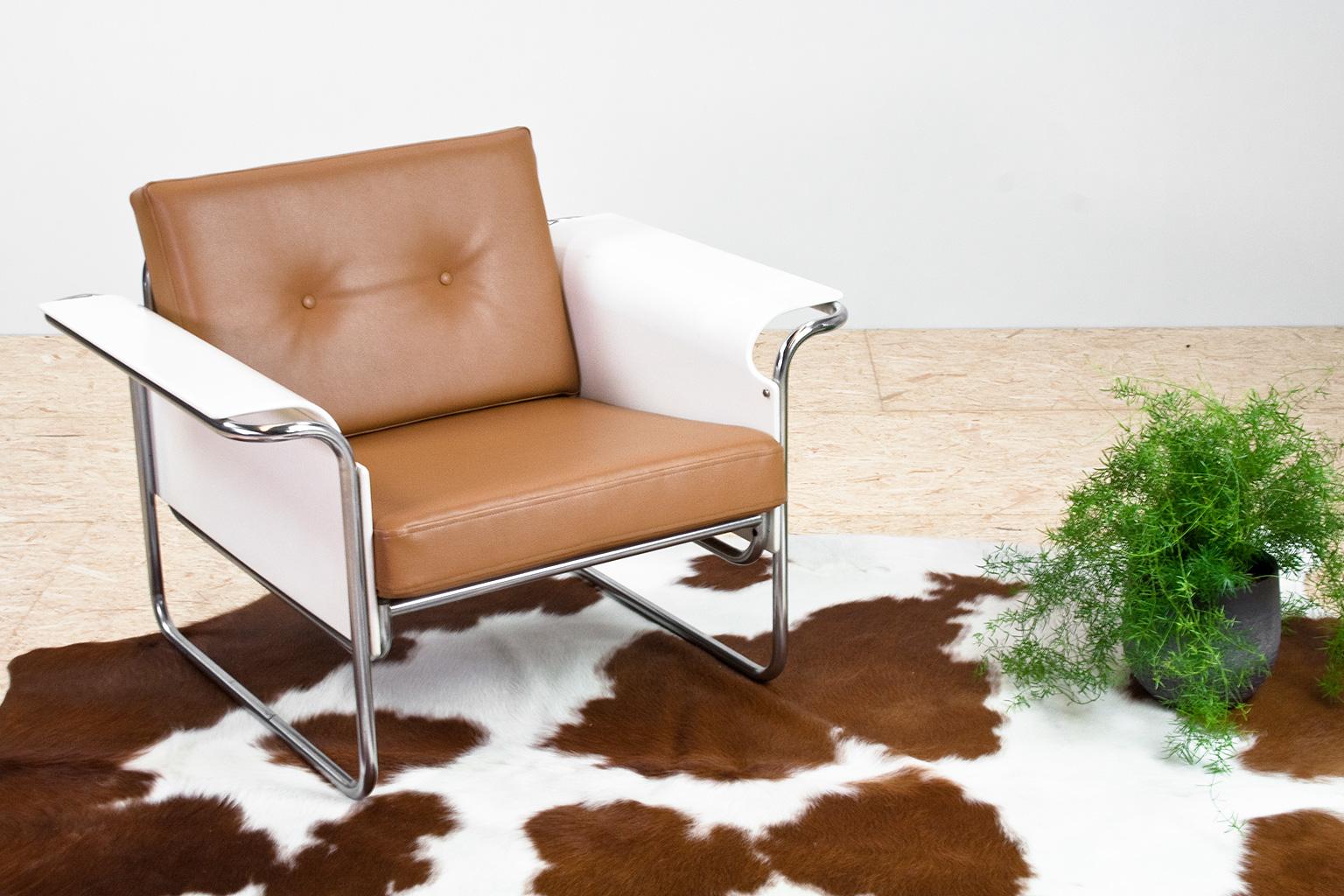 Scandinavian Modern armchair new upholstered in a tan colored faux leather upholstery. The flared armrests are made of (white lacquered) bent plywood, placed in a chromed metal tubular frame that without a doubt was inspired by the Bauhaus