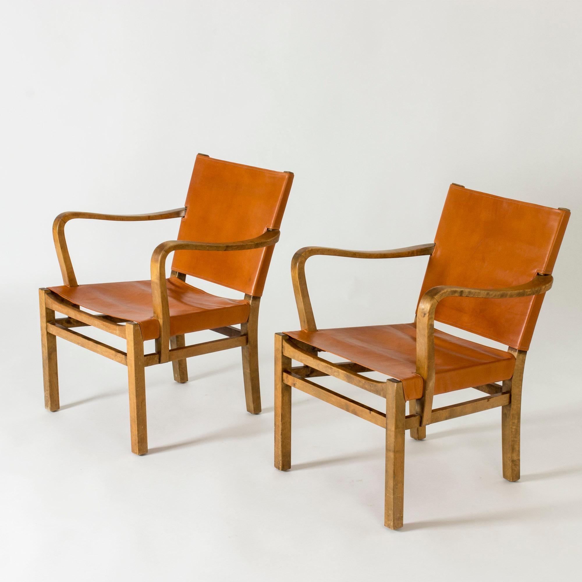 Pair of elegant armchairs by Elias Svedberg, made from birch with flowing lines and an open silhouette. Upholstered with supple brown leather.