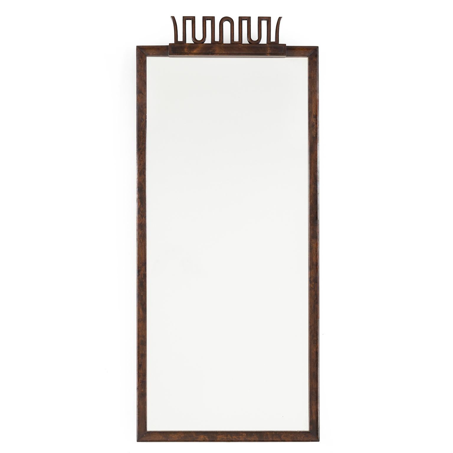 Scandinavian Modern, elegant Swedish Art Deco mirror by Axel Einar Hjorth for NK (Nordiska Kompaniet) Stockholm circa 1920s. The frame is stained and polished birch with a stylized carved wood 