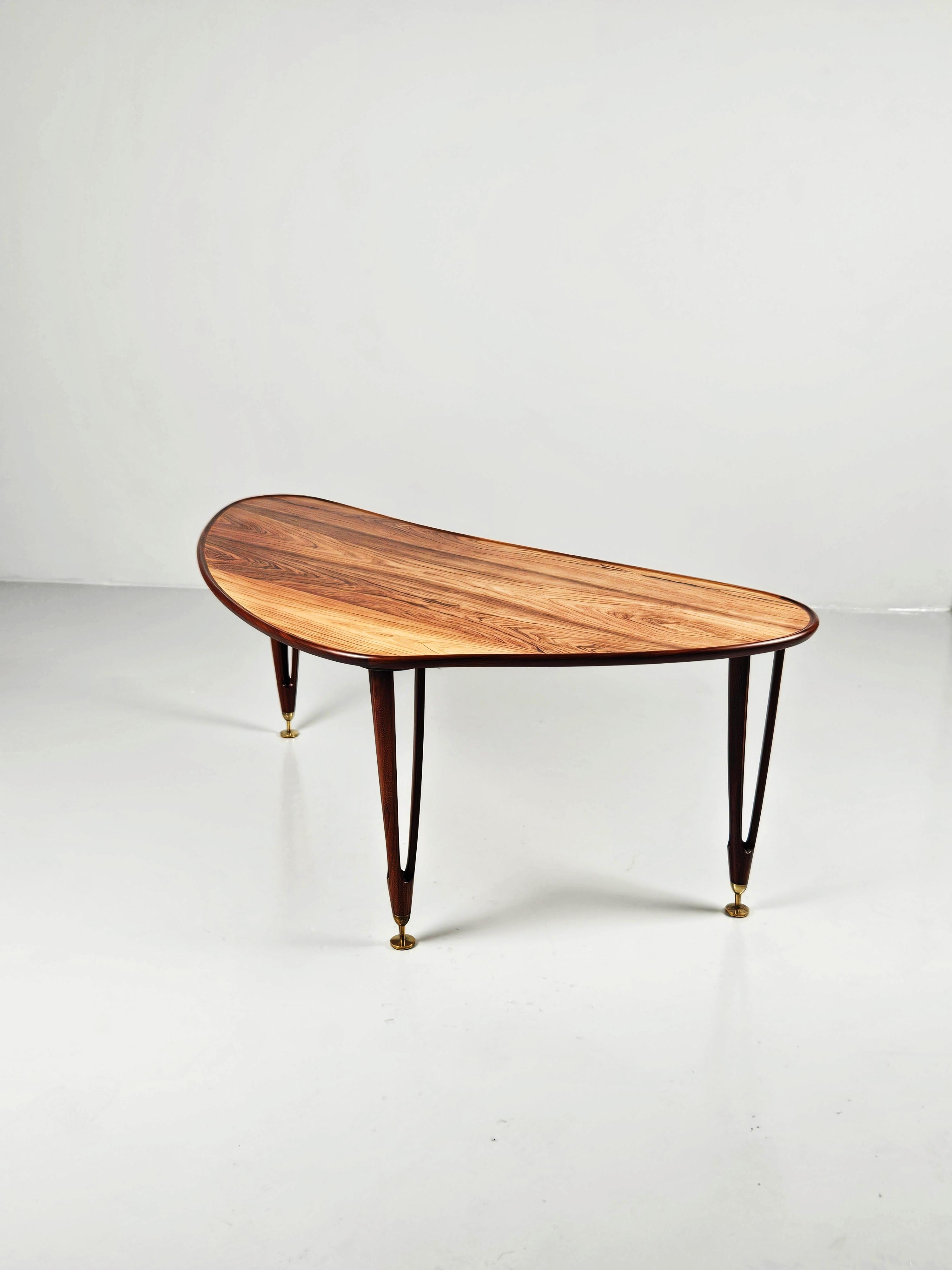 Rare sofa table with an asymmetrical shape produced by BC Møbler in Denmark during the 1960s. 

Unknown designer. 

Elegant and luxurious design with its rosewood top and brass feet. 