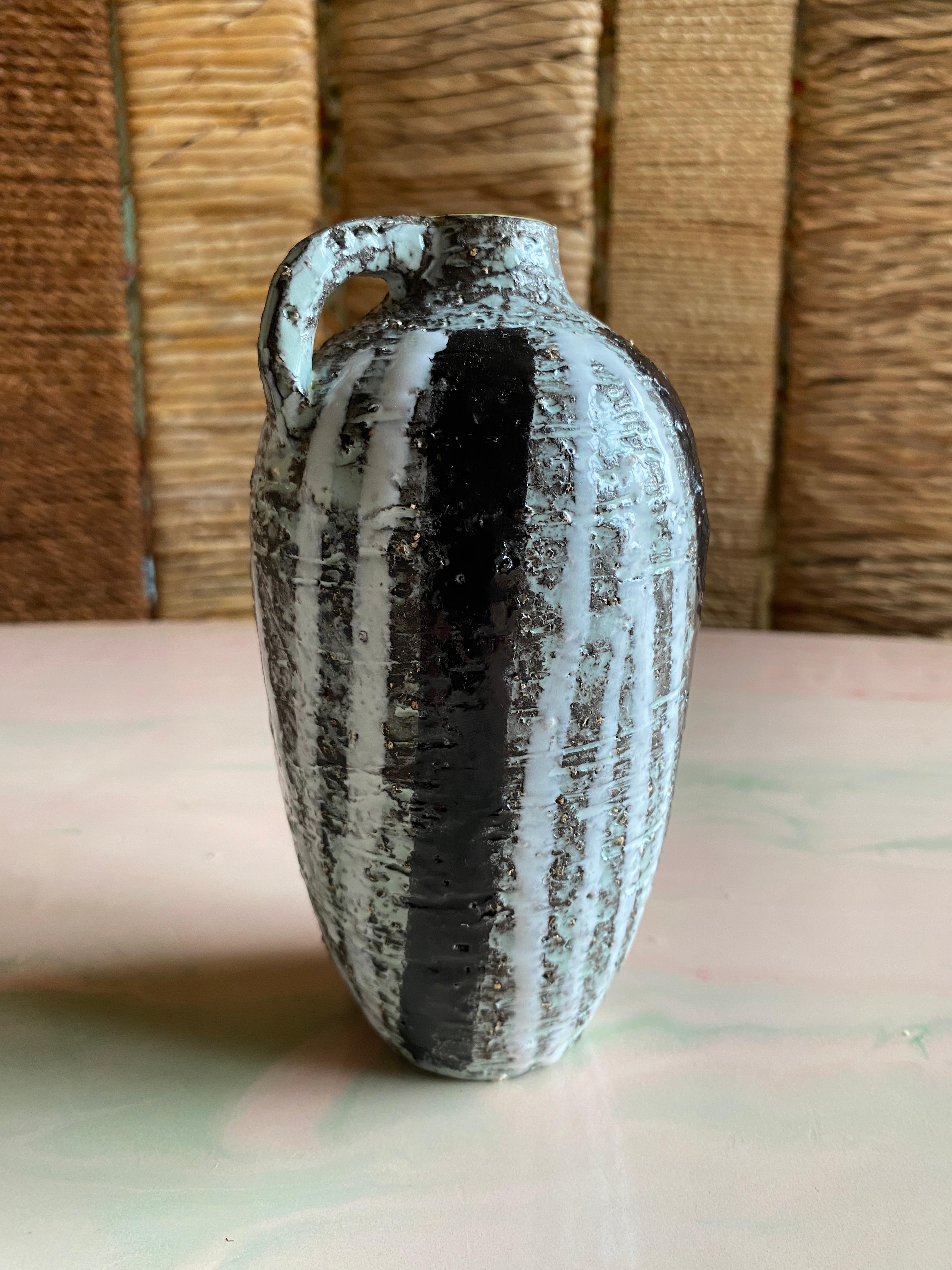 Realizzato dalla rinomata ceramista Ingrid Atterberg per Uppsala Ekeby, questo vaso in chamotte nera, bianca e grigia con un manico distintivo e una superficie ruvida incarna il design moderno scandinavo di metà secolo. 

Ingrid Atterberg