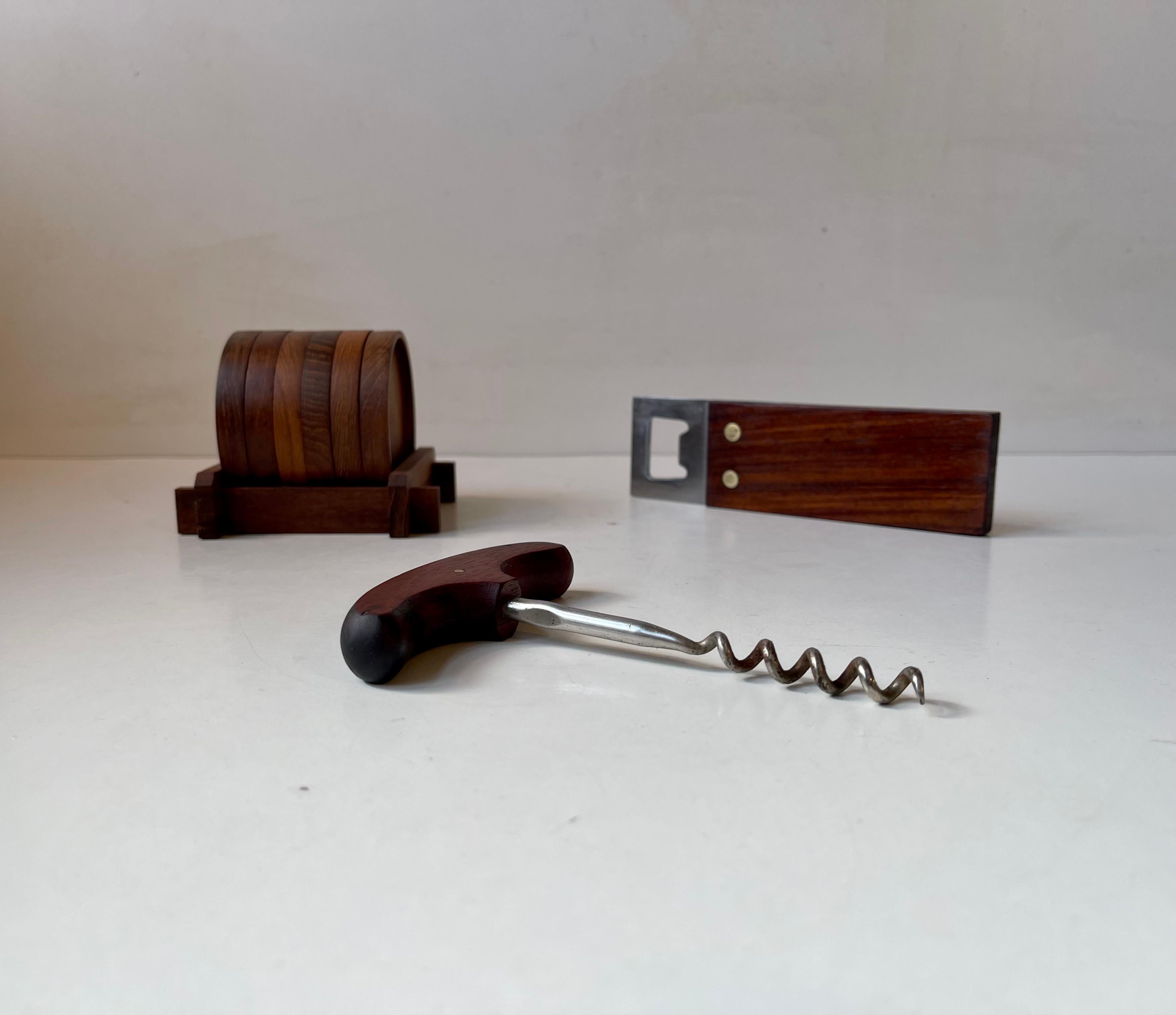 Midcentury bar-set with the following accessories: lime/cheese knife, Corkscrew with solid teak handle, rectangular large bottle opener in teak, stainless steel and featuring over-sized brass bolts and finally a set of 6 drink coasters in a rack of