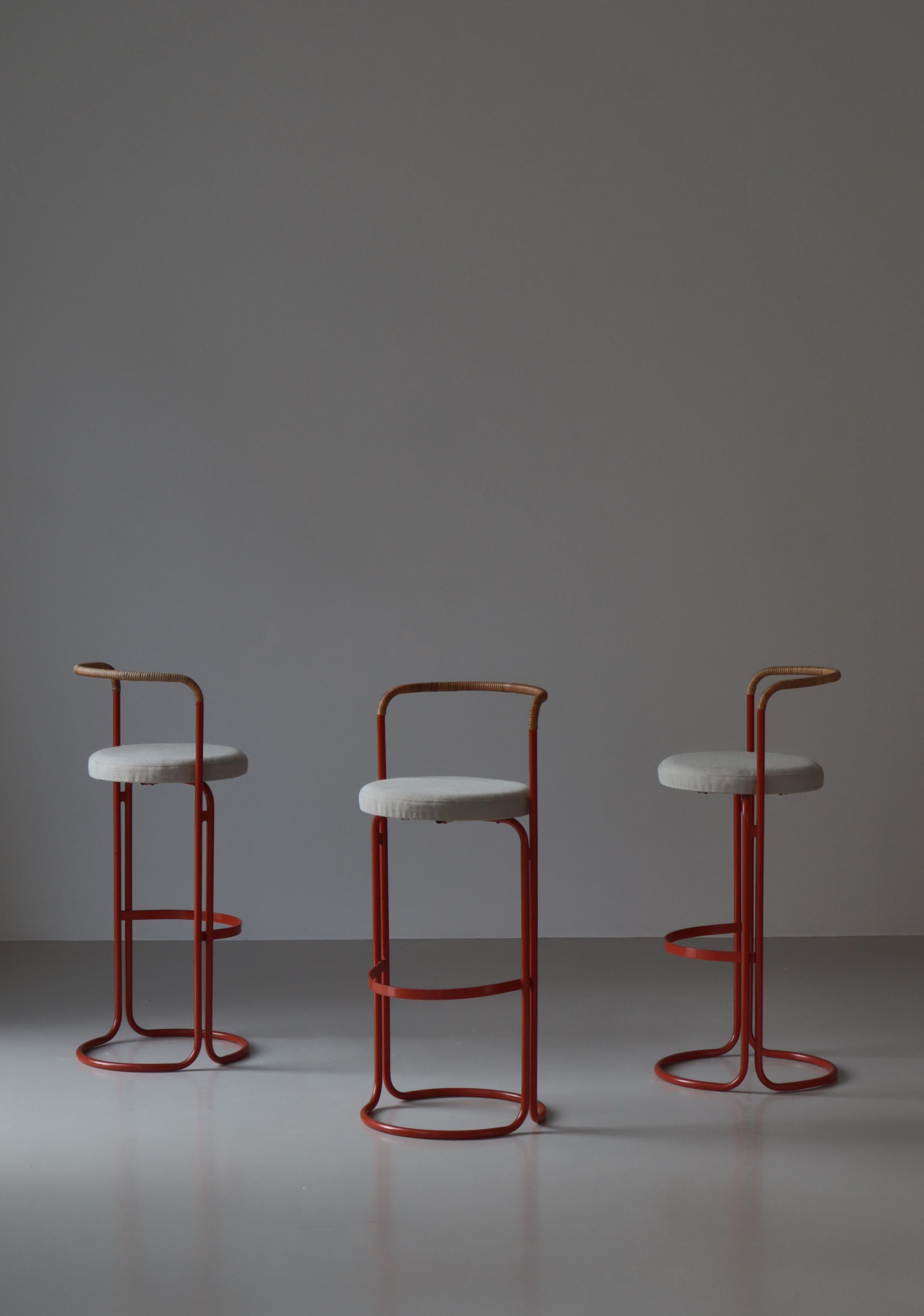Very rare set of 3 large bar stools by Danish Designer Poul Nørreklit. Made in red lacquered tubular steel, rattan cane and canvas seats. Produced in the 1960s.