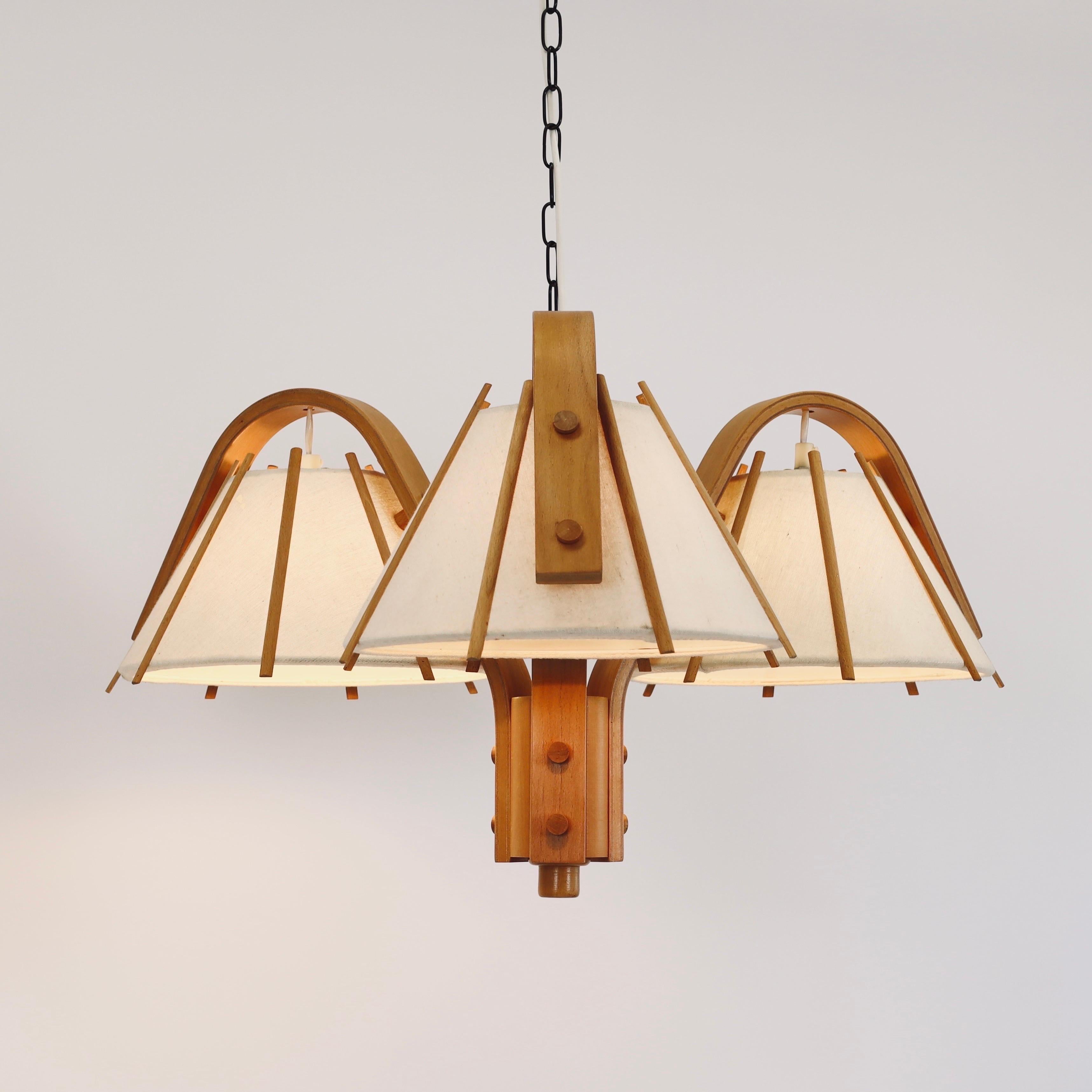 Impressive Scandinavian Modern pendant light in bend Beech wood with three canvas shades. A center piece for a beautiful home designed by Jan Wickelgren in the 1970s for Aneta Sweden. 

* A pendant light bend beech veneer with three cream-coloured