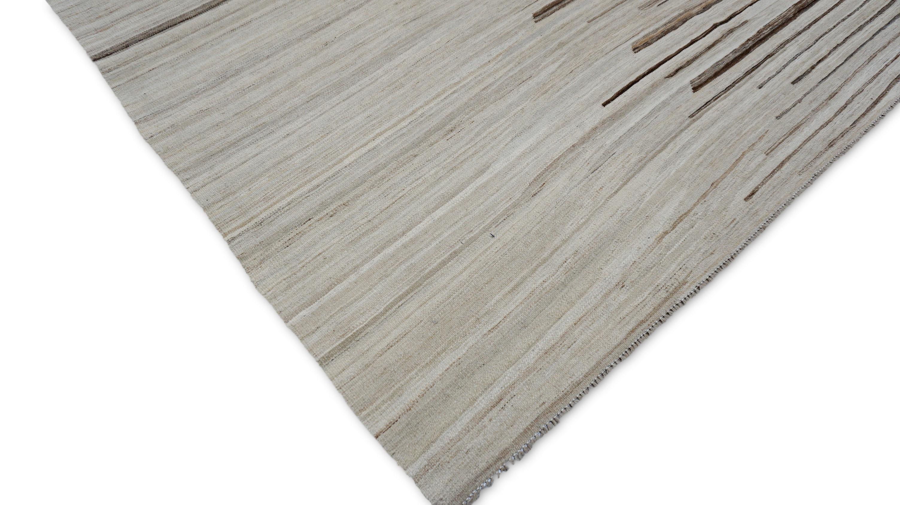 Questo pezzo è un kilim di lana tessuto a mano, realizzato in uno stile moderno e minimalista che fonde l'artigianato tribale con l'estetica contemporanea. Essendo un kilim a trama piatta, è caratterizzato da una struttura a basso profilo tessuta