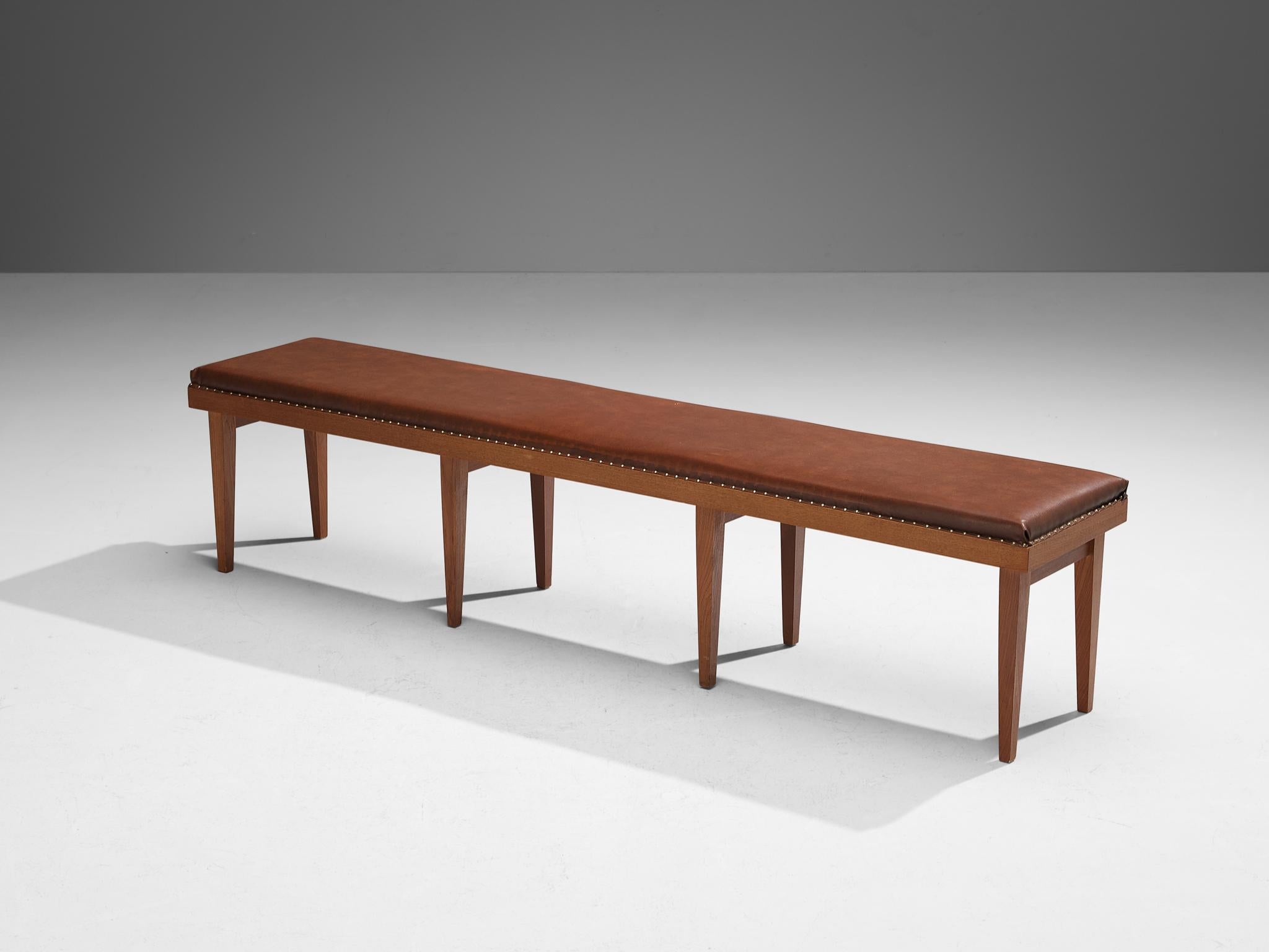 Panca grande, ecopelle, teak, ottone, Scandinavia, anni '50

Un mobile affascinante che emana un senso di armonia e purezza. La panca, di forma rettangolare, presenta una seduta imbottita in una ricca tonalità marrone-rossastra. I chiodi in ottone
