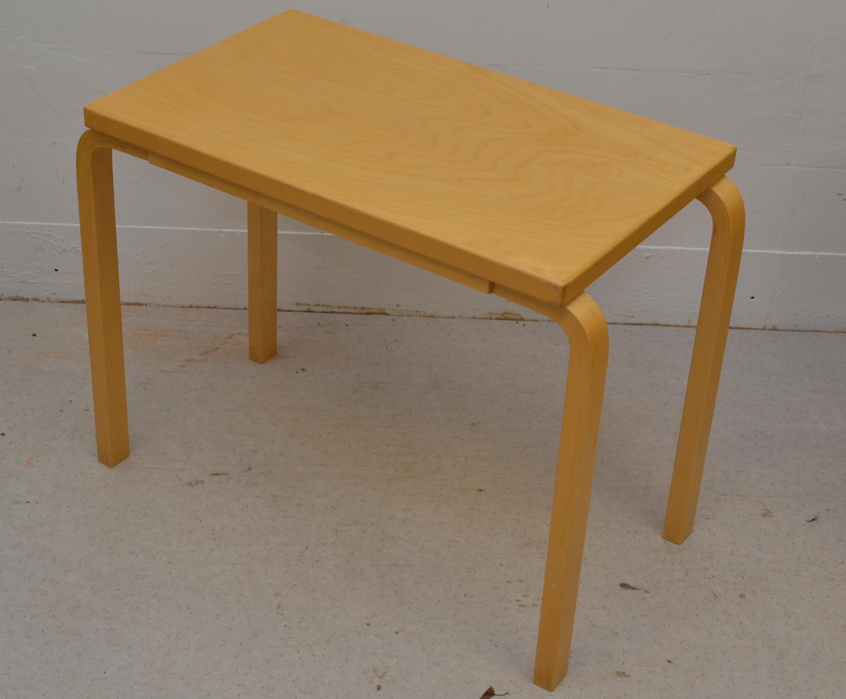 Classic Alvar Aalto side table produced by Artek in 2002, featuring the designer’s iconic L-leg construction which was a revolutionary bent-wood technique introduced in the 1930s. The model was originally designed in 1935, and it remains one of