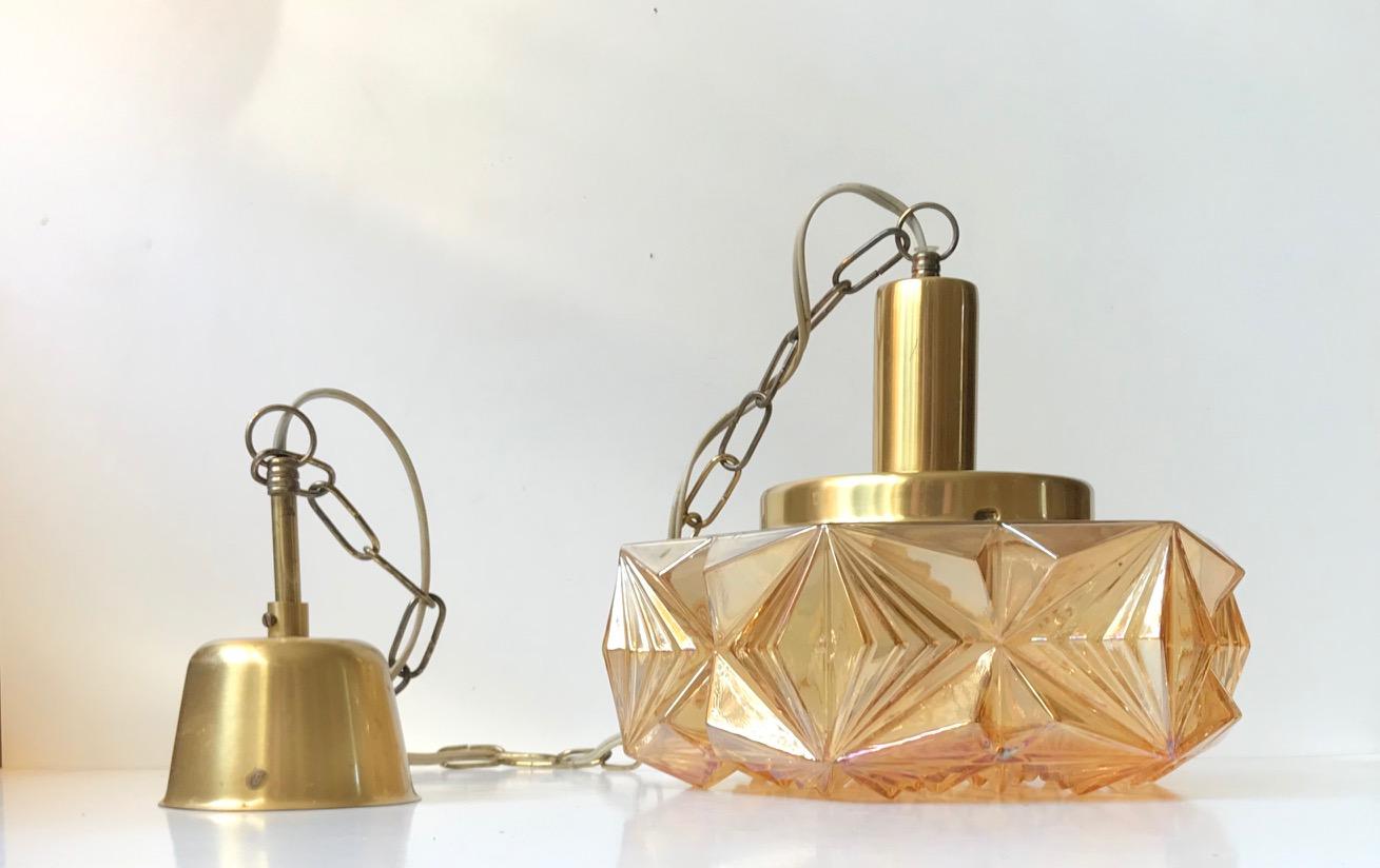 This pendant light was designed and manufactured by Danish design trio Vitrika in the 1960s. The name Vitrika, or Vi-Tri-Ka means 'The three of us can do it'. The lamp features a geometric outer amber colored glass shade and a top, chain and
