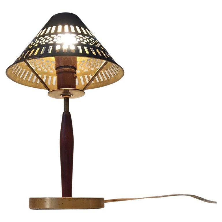 A small Scandinavian table light in patinated solid brass and teak. It has a solid brass shade with geometric perforations. It was manufactured by ASEA in Sweden during the 1950s in a style reminiscent of Hans Bergstrom and Sonja Katzin.