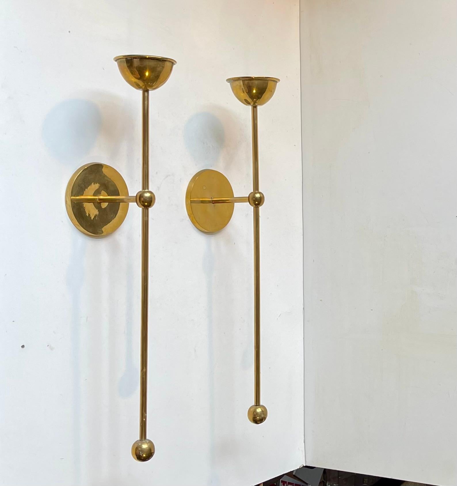 Ein Paar wandmontierte Kerzenhalter aus massivem Messing von einem dänischen Designer/Hersteller aus den 1960-70er Jahren. Erinnert im Stil an Stücke von Quistgaard und Pierre Forssell. Für Kerzen in normaler Größe.   Abmessungen: 

H: 45/43 cm